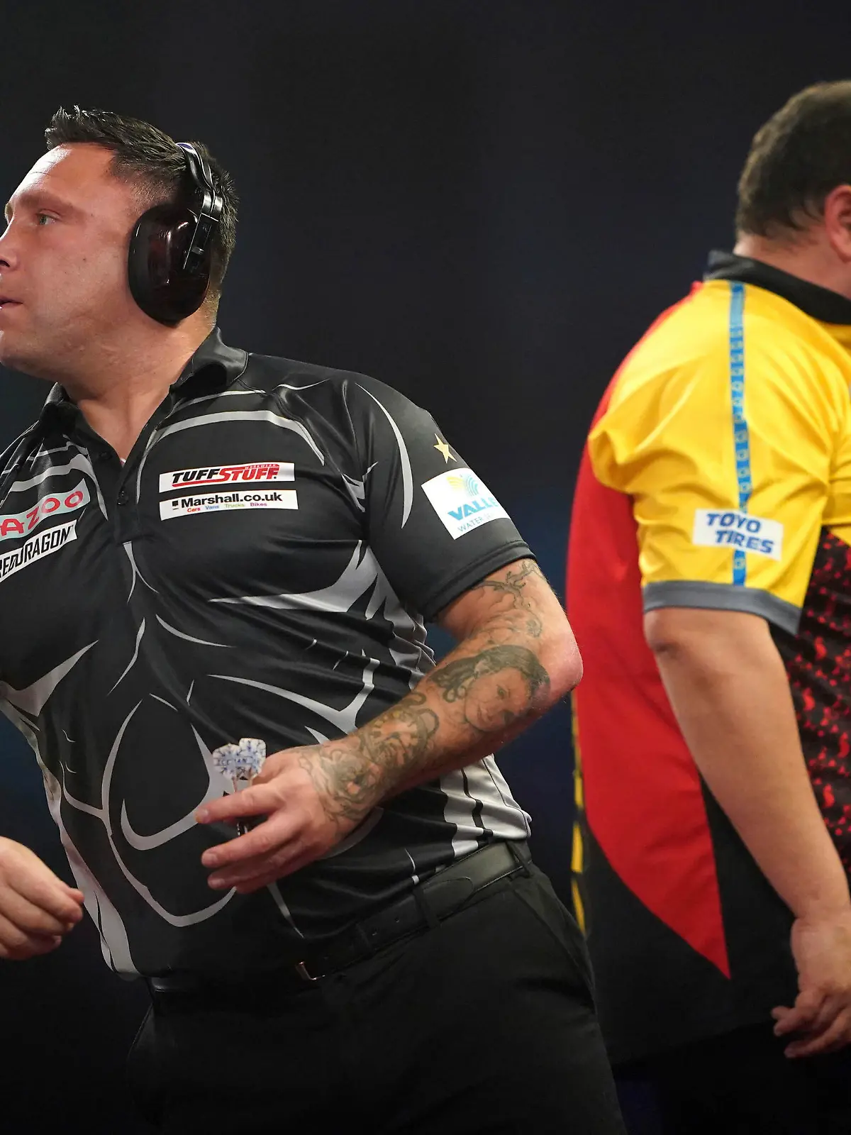 Wales' Gerwyn Price wears ear defenders as he plays against Germany's Gabriel Clemens, during day fourteen of the World Darts Championship at Alexandra Palace, in London, Sunday, Jan. 1, 2023. (Zac Goodwin/PA via AP)