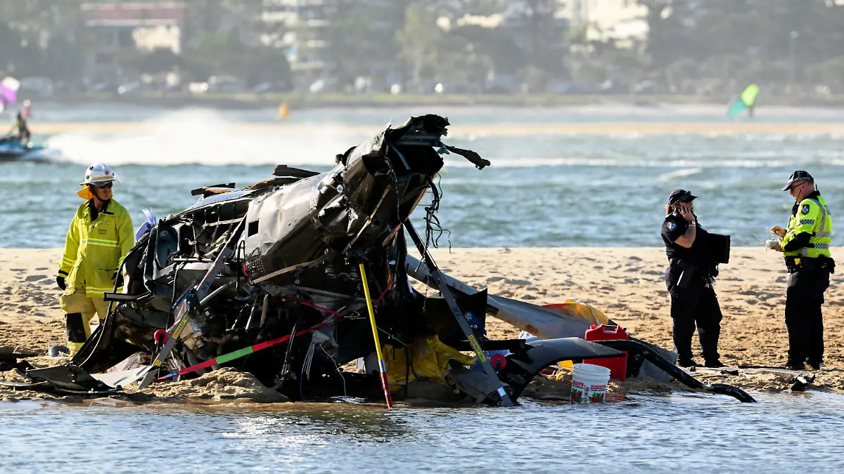 Emergency workers inspect a helicopter at a scene collision near Seaworld, on the Gold Coast, Australia, Monday, Jan. 2, 2023. Two helicopters collided killing several passengers and critically injuring a few others in a crash that drew emergency aid from beachgoers enjoying the water during the southern summer. (Dave Hunt/AAP Image via AP)
