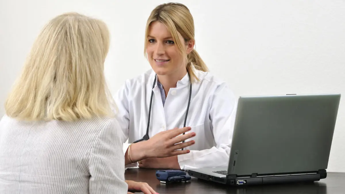 Ärztin mit Patientin im Gespräch am Tisch mit Computer
model released
