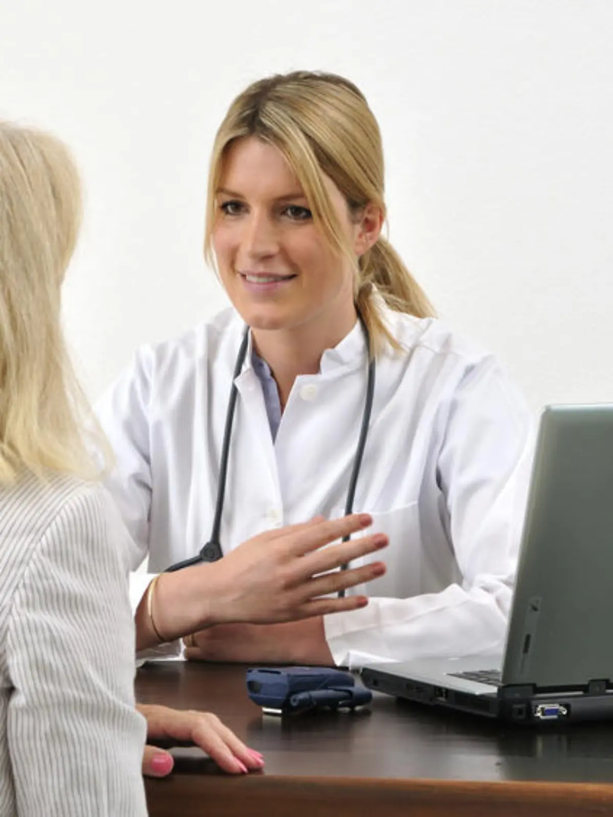 Ärztin mit Patientin im Gespräch am Tisch mit Computer 


model released