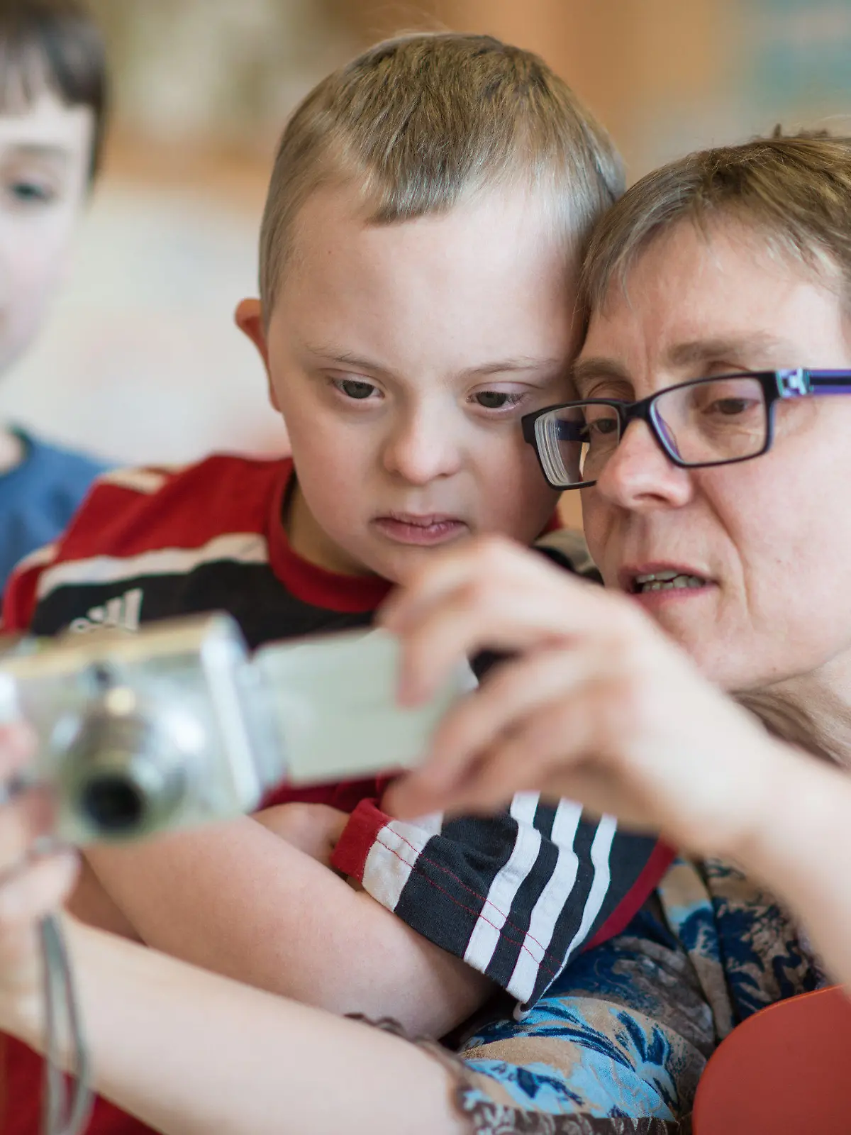 Der Viertklässler Henri (M), ein Kind mit Down-Syndrom, betrachtet am 27.03.2014 in Walldorf (Baden-Württemberg) in der Schillerschule zusammen mit seiner Mutter Kirsten Erhardt und Mitschülern die Fotos einer Digitalkamera. Vier Jahre lang hat Henri gemeinsam mit seinen Klassenkameraden gelernt und gespielt. Nach der Grundschule möchte der Elfjährige mit Down-Syndrom gern wie seine Freunde aus Walldorf im Rhein-Neckar-Kreis aufs Gymnasium wechseln. Er wäre eines der ersten behinderten Kinder an einem Südwest-Gymnasium, das anders als seine Mitschüler das angestrebte Bildungsziel nicht erreichen kann. Foto: Uwe Anspach/dpa (zu lsw-Korr: «Offene Fragen der Inklusion: Down-Syndrom-Kind will aufs Gymi» vom 07.04.2014) +++(c) dpa - Bildfunk+++