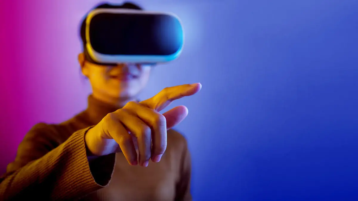 Asian woman wearing VR glasses pointing finger to do activities in the virtual world on blue and purple background.
