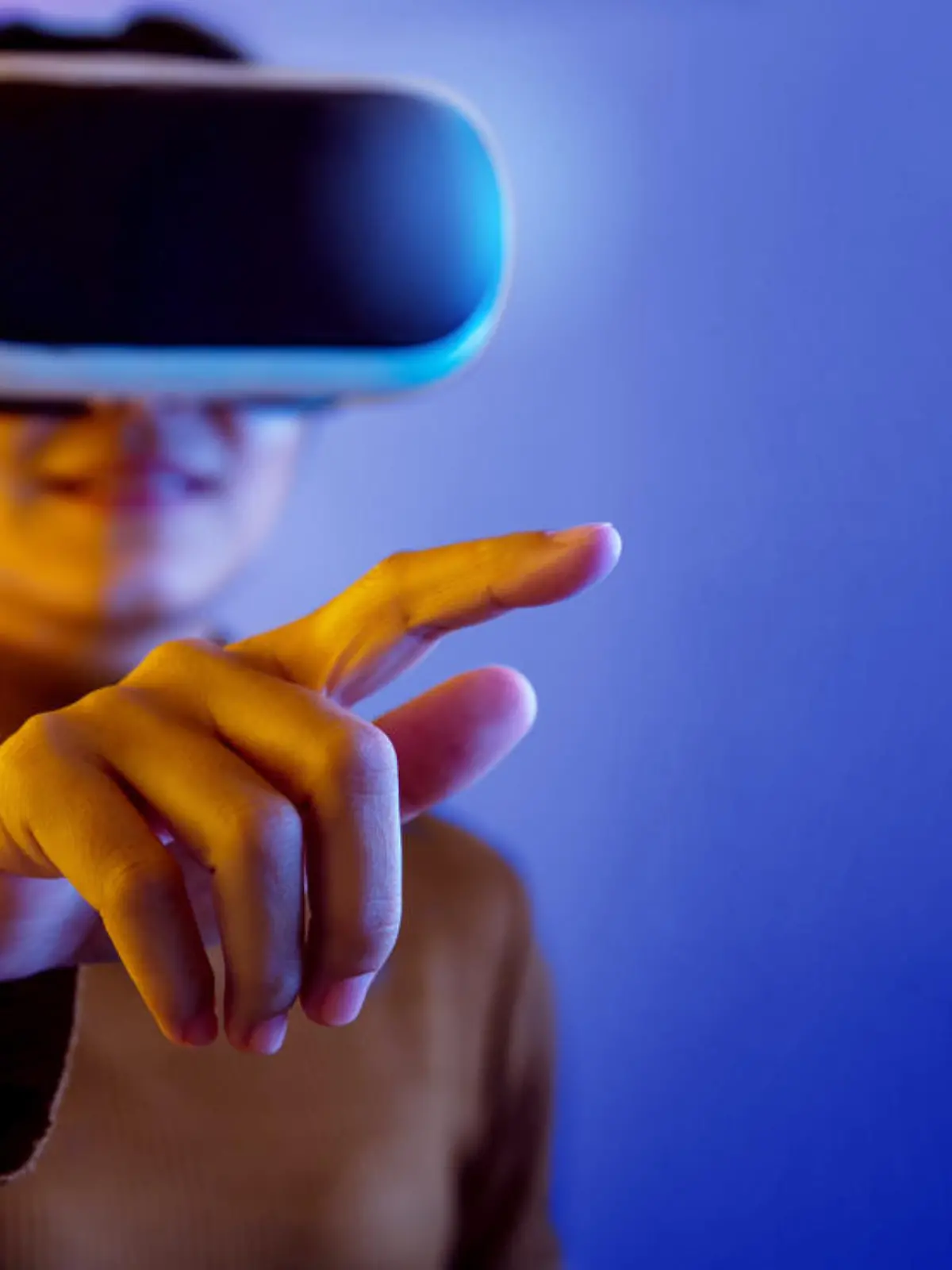 Asian woman wearing VR glasses pointing finger to do activities in the virtual world on blue and purple background.