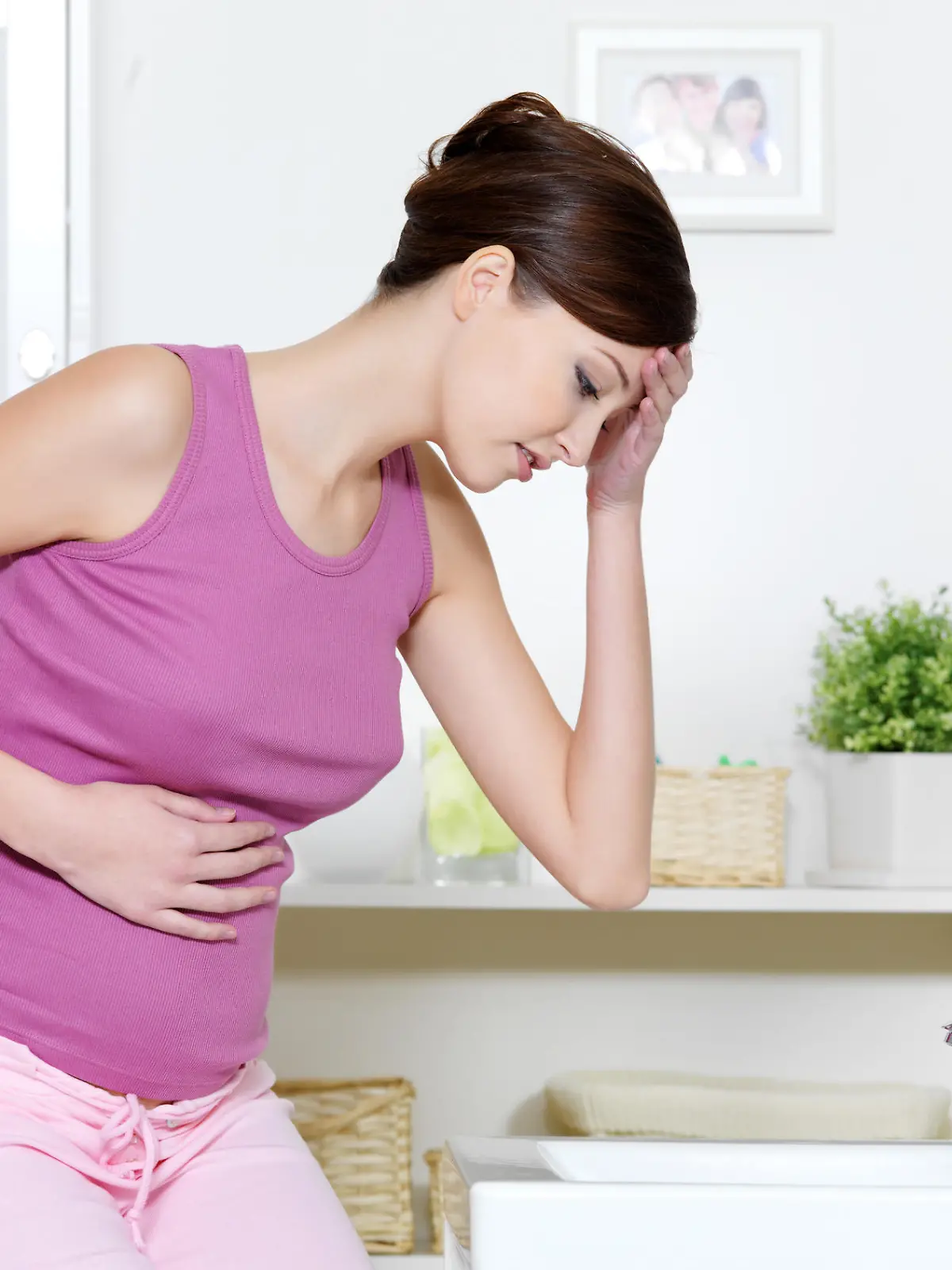 Pregnant woman with strong pain of stomach and nausea sitting in bathroom