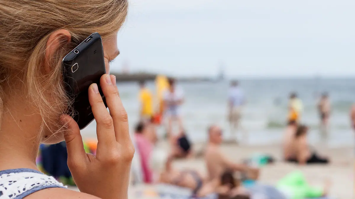 ARCHIV - ILLUSTRATION - Eine Frau telefoniert am 04.08.2013 mit einem Mobiltelefon am Strand von Kolberg, Polen, an der Ostsee. 71 Prozent der Arbeitnehmer in Deutschland sind auch im Urlaub für den Chef erreichbar. 58 beziehungsweise 59 Prozent sind per Telefon oder über Messenger-Dienste wie Whatsapp erreichbar. (zu dpa "Großteil der Arbeitnehmer ist auch im Urlaub erreichbar" vom 18.07.2017) Foto: Daniel Naupold/dpa +++(c) dpa - Bildfunk+++