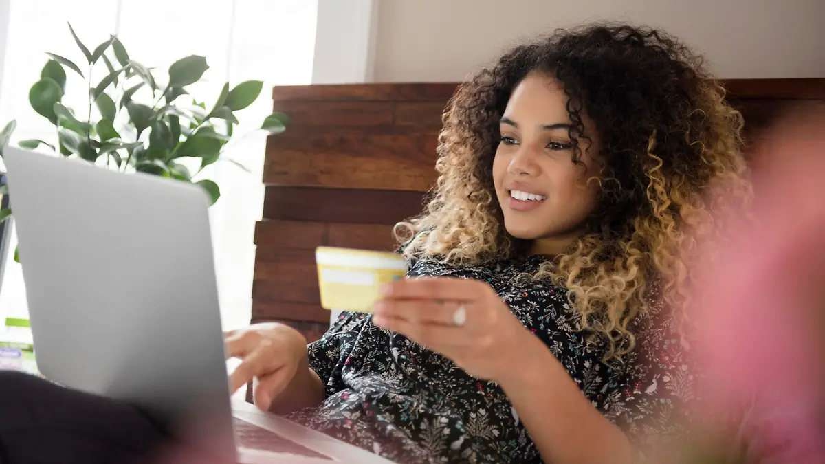 Mixed Race woman laying on bed online shopping with laptop, Gemischte Abstammung Frau auf dem Bett legt die online mit Laptop-Shopping || Modellfreigabe vorhanden