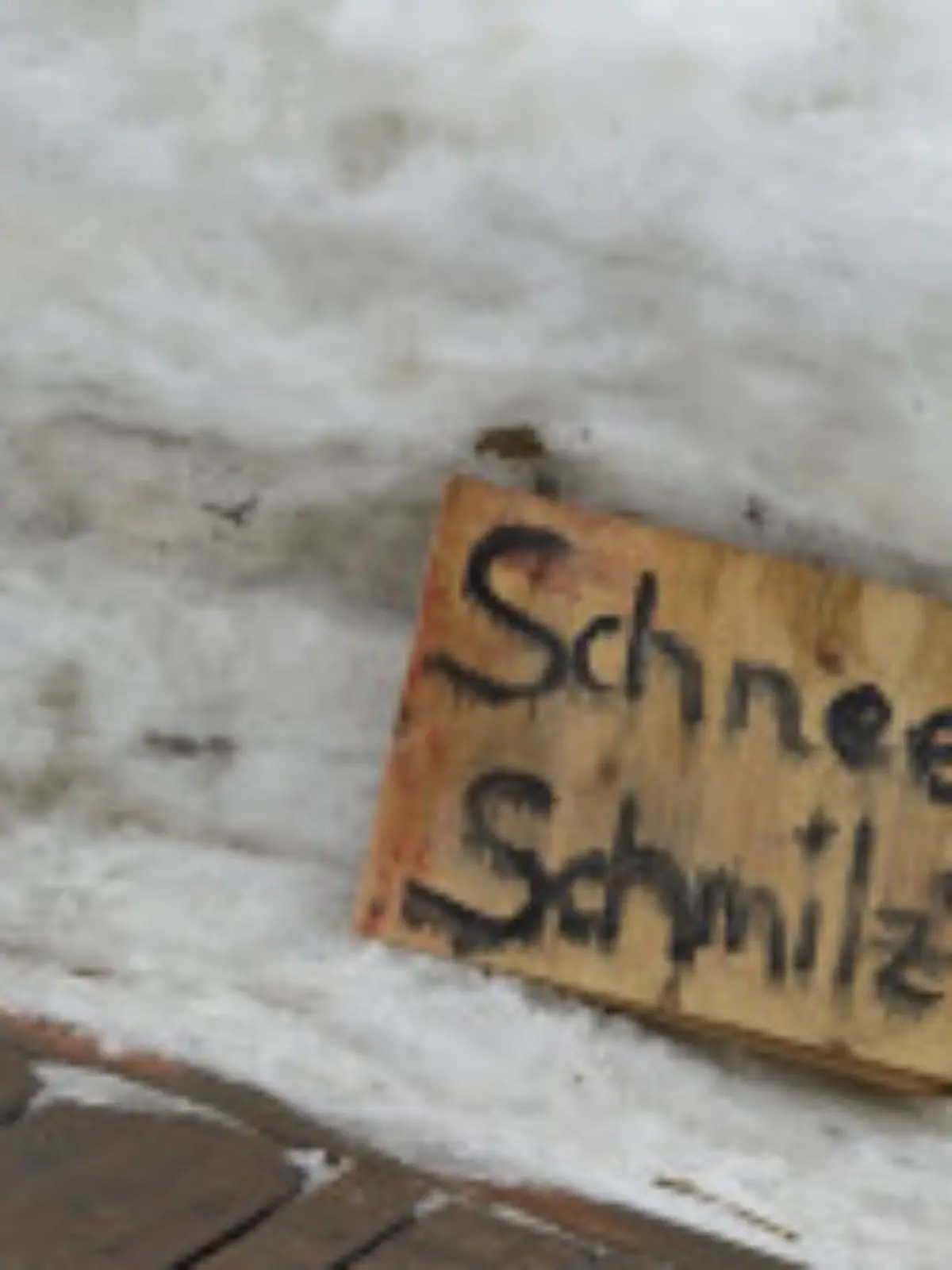 Ein Kind hebt am Freitag (19.02.2010) einen Schneeklumpen neben einem Schneemann mit einem Schild "Schnee schmilzt" auf dem Schlossplatz in Berlin, wo im Rahmen einer "Schneemann-Demo" Schneefiguren aufgestellt waren. Bei Temperaturen zwischen drei und fünf Grad taut die Hauptstadt langsam auf. Foto: Arno Burgi dpa/lbn  +++(c) dpa - Bildfunk+++