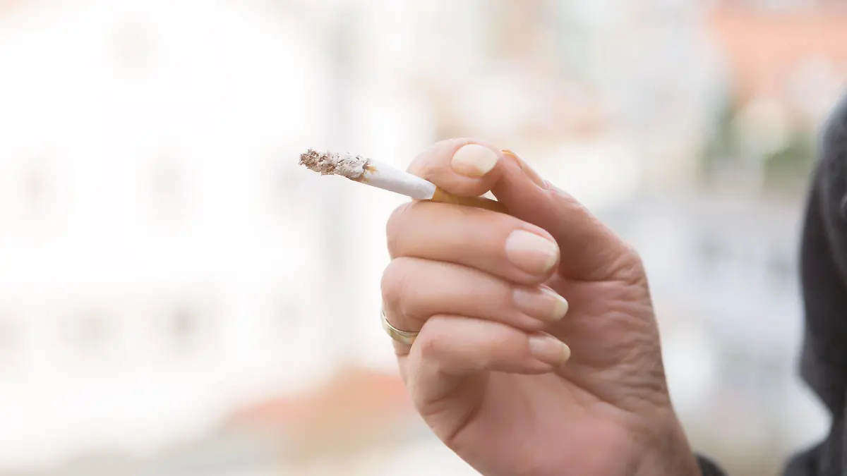 Hand of a woman smoking a cigarette holding it between her fingers with a long plume of ash at the tip over a blurred outdoor background Hand of a woman smoking a cigarette Copyright: xJuliaxPfeiferx