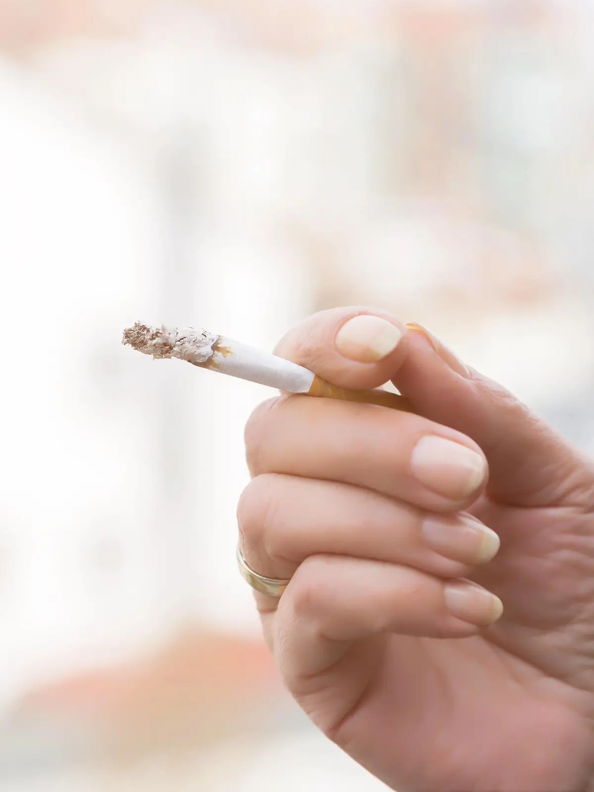  Hand of a woman smoking a cigarette holding it between her fingers with a long plume of ash at the tip over a blurred outdoor background Hand of a woman smoking a cigarette Copyright: xJuliaxPfeiferx