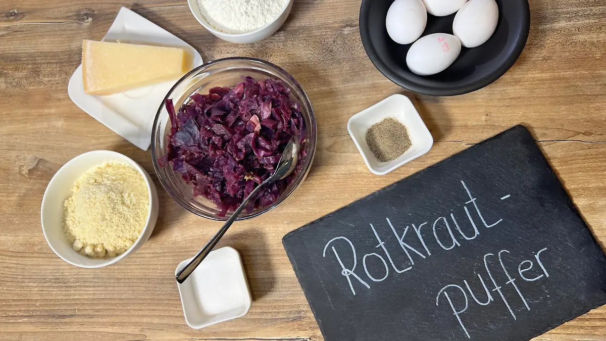 Man sieht auf diesen Bild alle benötigten Zutaten und eine Schiefertafel in der rechten Ecke mit der Aufschrift: Rotkrautpuffer