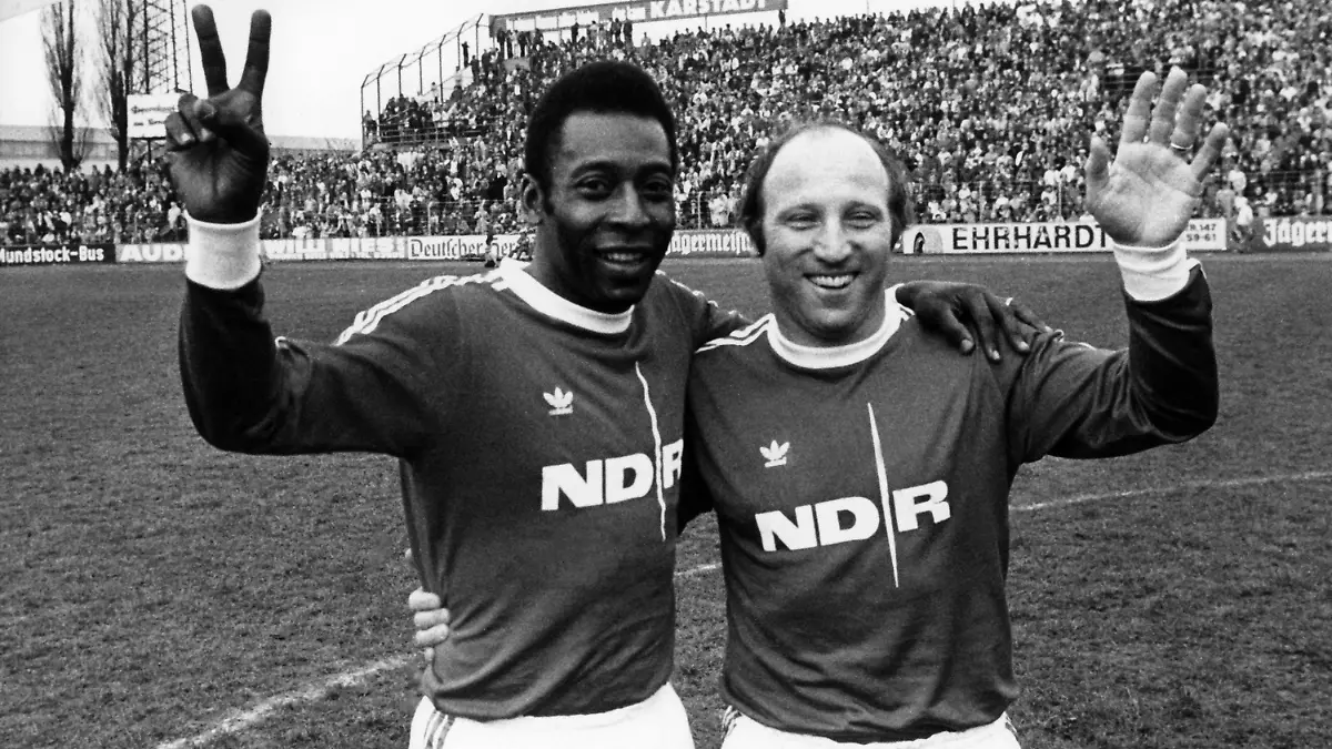 ARCHIV - 21.04.1975, Niedersachsen, Braunschweig: Der Ehrenspielführer der deutschen Fußball Nationalmannschaft, Uwe Seeler (r), und die brasilianische Fußball-Legende Pele winken bei einem Benefizspiel im Eintrachtstadion für die Fernsehlotterie "Ein Platz an der Sonne". Die brasilianische Fußball-Legende Pelé ist im Alter von 82 Jahren gestorben. Foto: Wolfgang Weihs/dpa +++ dpa-Bildfunk +++