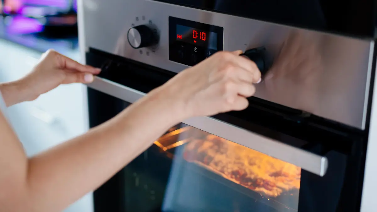 Auflauf kochen: Frau stellt den Timer am Backofen ein