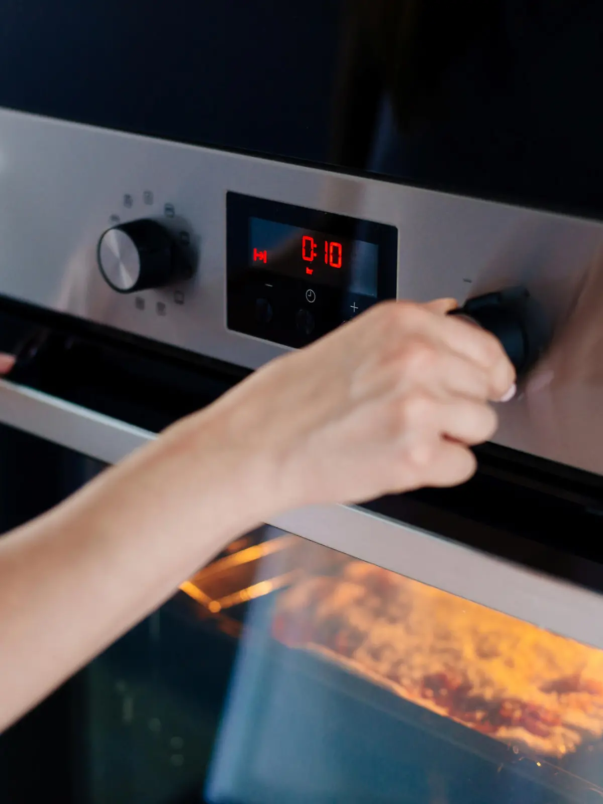 Auflauf kochen: Frau stellt den Timer am Backofen ein