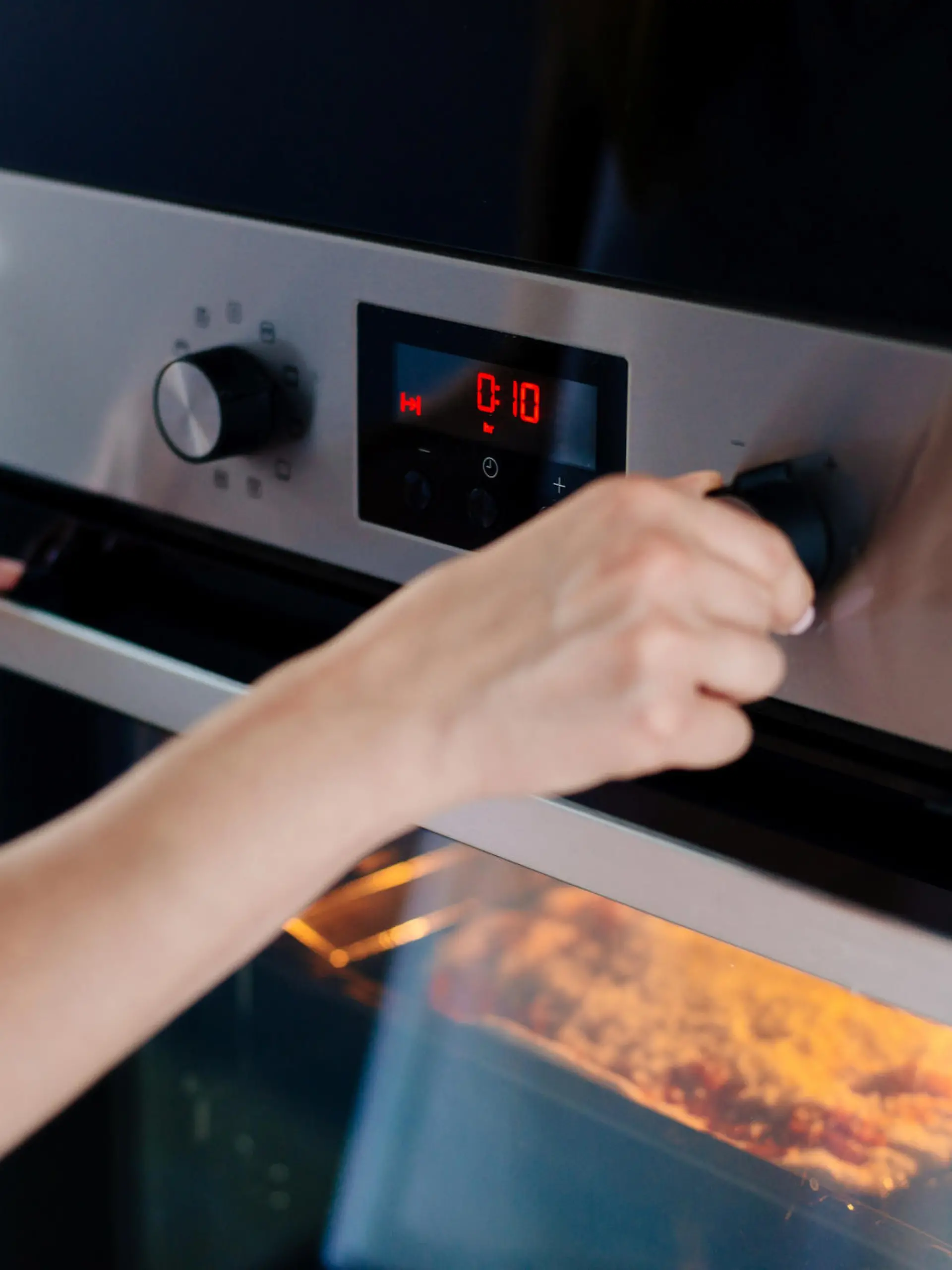Auflauf kochen: Frau stellt den Timer am Backofen ein