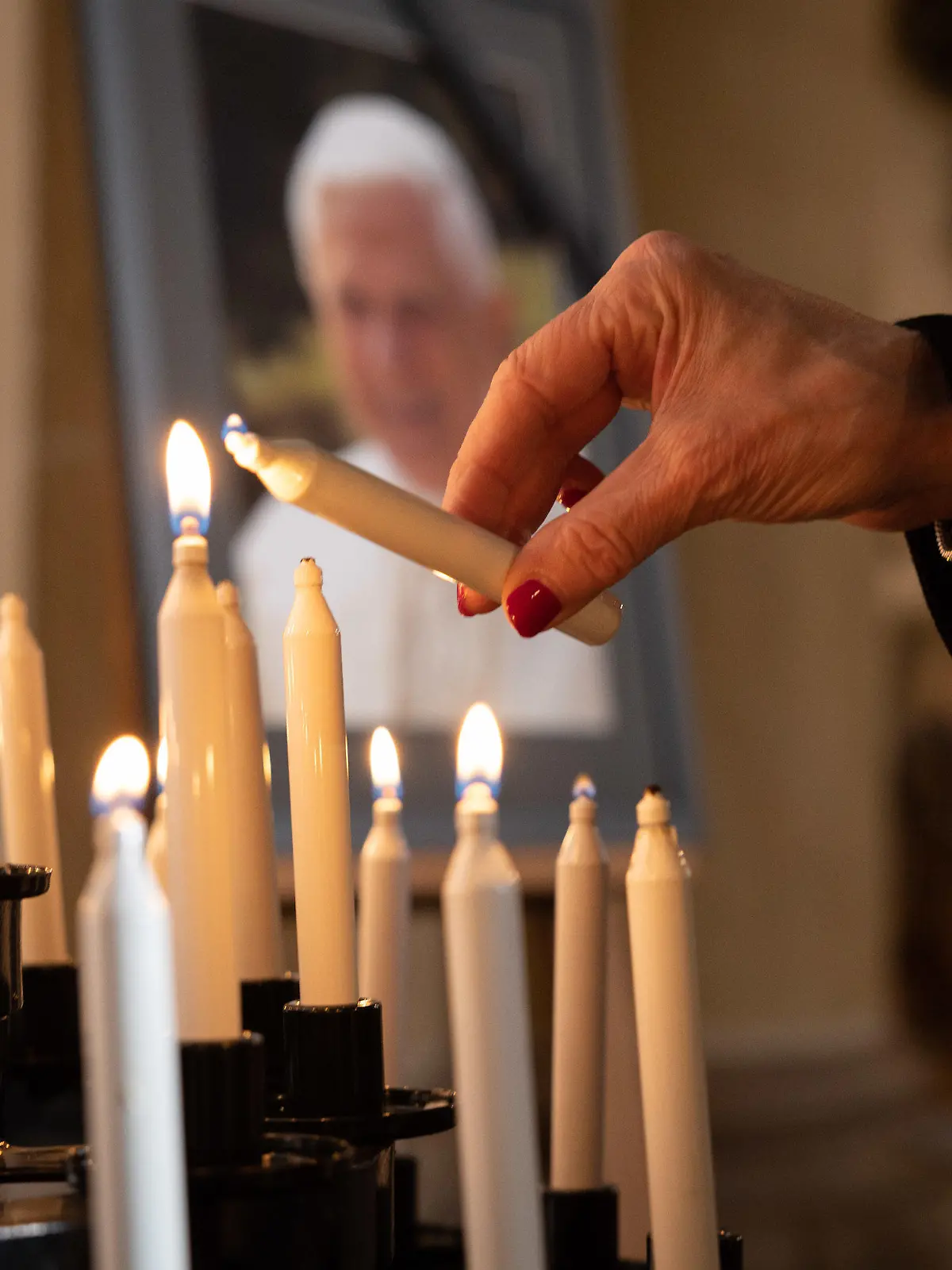 31.12.2022, Nordrhein-Westfalen, Paderborn: Eine Frau entzündet eine Kerze im Dom St. Maria, St. Liborius, St. Kilian von Paderborn für den emeritierten Papst Benedikt XVI.. Der emeritierte Papst Benedikt XVI. ist am 31.12.2022 im Alter von 95 Jahren im Vatikan gestorben. Foto: Friso Gentsch/dpa +++ dpa-Bildfunk +++
