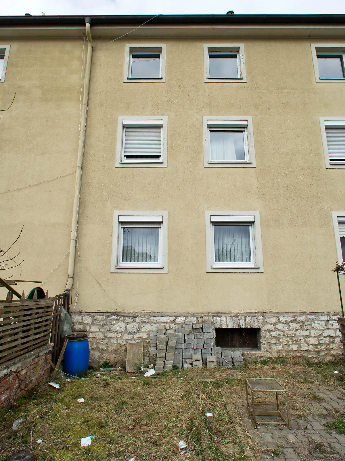 Blick auf ein Mehrfamilienhaus und den dazugehörigen Garten am 19.03.2014 in Treuchtlingen (Bayern), wo sich im obersten Geschoss (M) am Vorabend ein Familiendrama ereignet hatte. Vermutlich aus Verzweiflung über die Trennung von seiner Frau hat ein 30-jähriger Vater seine drei kleinen Kinder aus dem Fenster seiner Wohnung in in den Garten geworfen. Anschließend sprang der Mann selbst hinterher. Nach dem Sturz aus dem zweiten Obergeschoss des Mehrfamilienhauses schwebte ein zehn Monate alter Junge in Lebensgefahr, seine zwei und drei Jahre alten Schwestern wurden wie ihr Vater schwer verletzt. Foto: Daniel Karmann/dpa +++(c) dpa - Bildfunk+++
