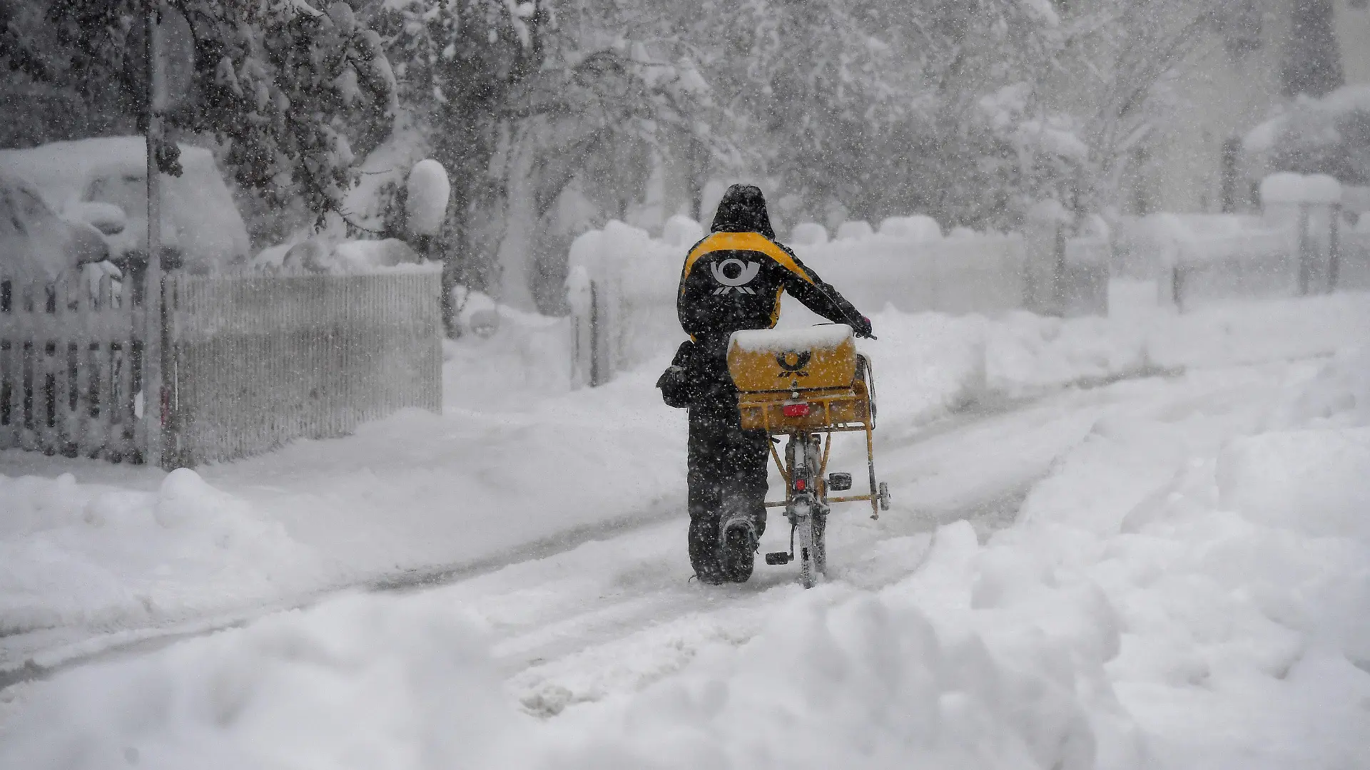 14.01.2021, Bayern, Garmisch-Partenkirchen: Ein Postbote schiebt sein Postfahrrad durch den Schnee. Innerhalb weniger Stunden sorgte eine Nordstaulage für viel frischen Schnee in den Bergen. Foto: Angelika Warmuth/dpa +++ dpa-Bildfunk +++