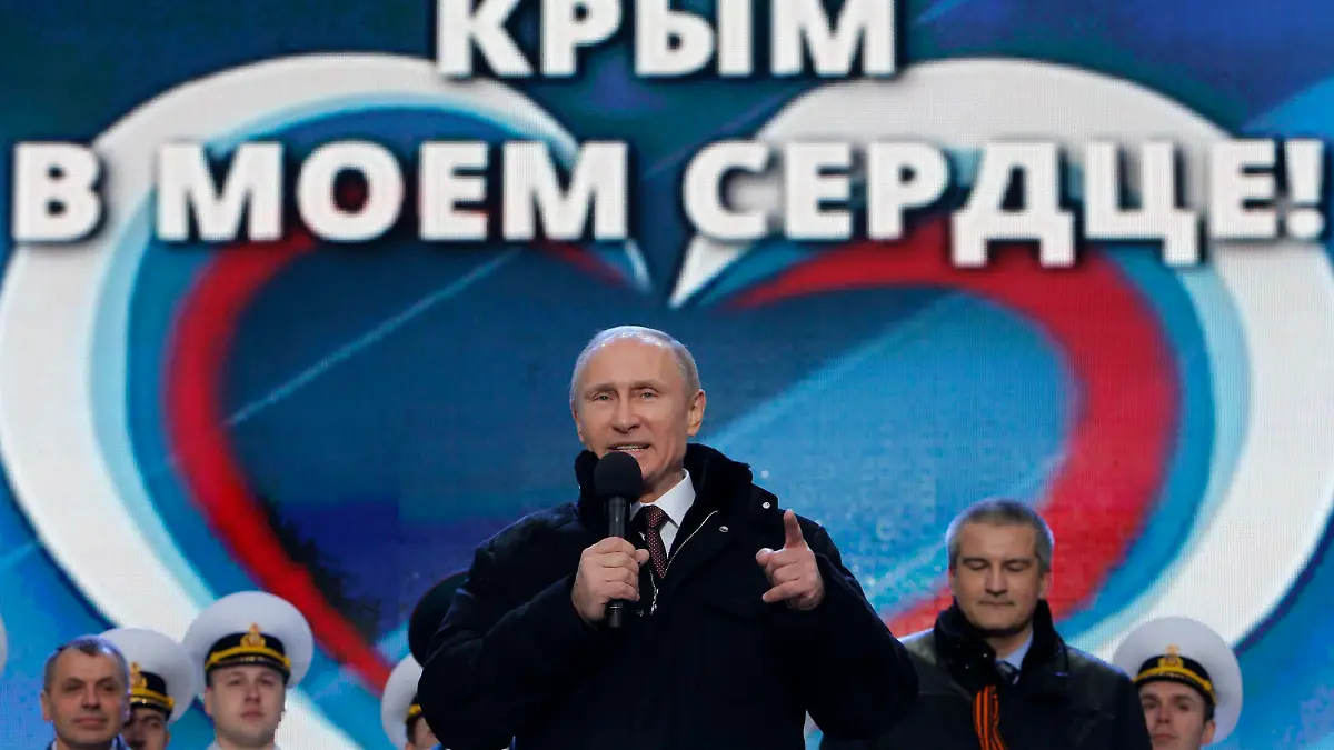 Russia's President Vladimir Putin (front) addresses the audience during a rally and a concert called "We are together" to support the annexation of Ukraine's Crimea to Russia, with Crimea's Prime Minister Sergei Aksyonov and parliamentary speaker Vladimir Konstantinov (L) seen in the background, at the Red Square in central Moscow, March 18, 2014. Russian President Vladimir Putin, defying Ukrainian protests and Western sanctions, signed a treaty on Tuesday making Crimea part of Russia but said he did not plan to seize any other regions of Ukraine. The words in the background read, "Crimea is in my heart!" REUTERS/Maxim Shemetov (RUSSIA - Tags: POLITICS)