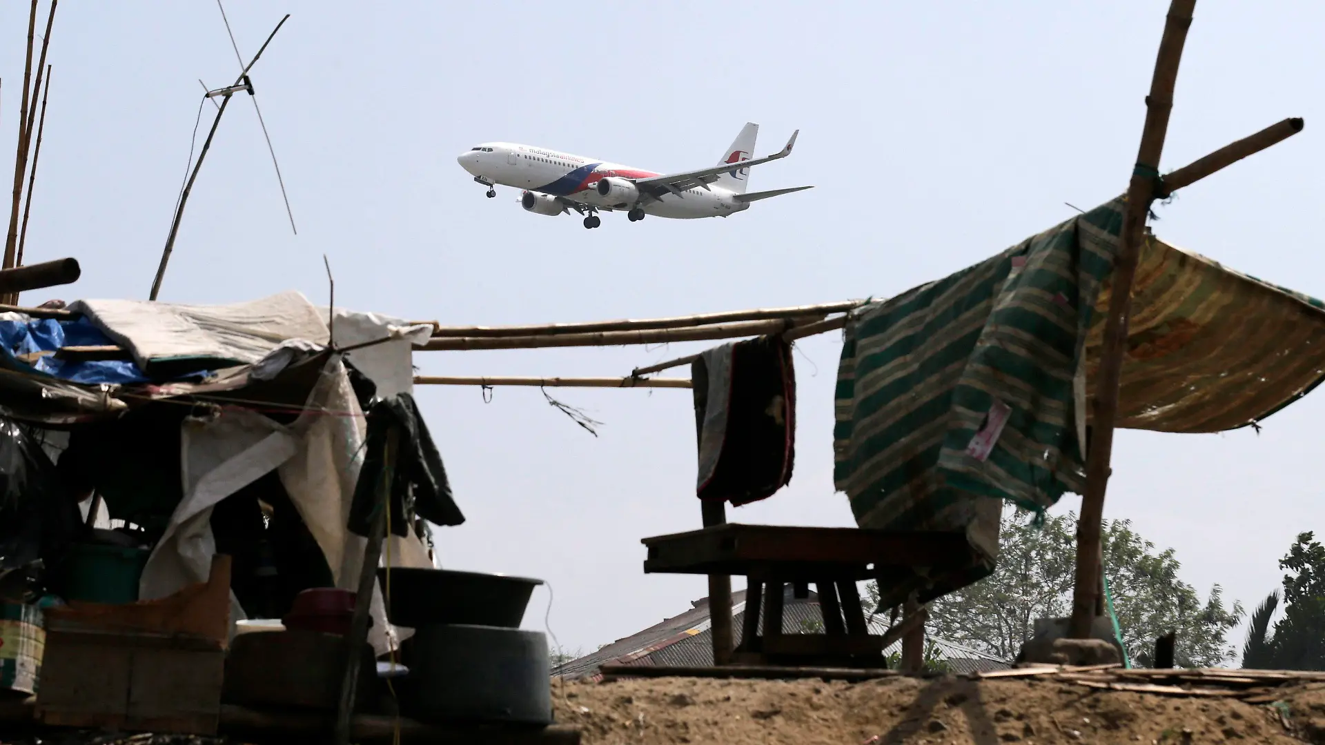 epa04129361 A Malaysia Airlines plane flies over shanties on the tenth day of the search of missing MH370A plane, in Manila, Philippines, 17 March 2014. According to report, Captain Zaharie Ahmad Shah, the pilot of the missing Malaysia Airlines Flight MH370 was trained at an aviaion school in the Philippines. The 52 year old pilot, born and raised in Penang in Malaysia, joined Malaysia Airlines in 1981 and was promoted to the rank of captain in the early 1990s. Malaysia Airlines flight MH370 with 239 people on board went missing early 08 March 2014 while on its way to Beijing. EPA/FRANCIS R. MALASIG DIS +++(c) dpa - Bildfunk+++