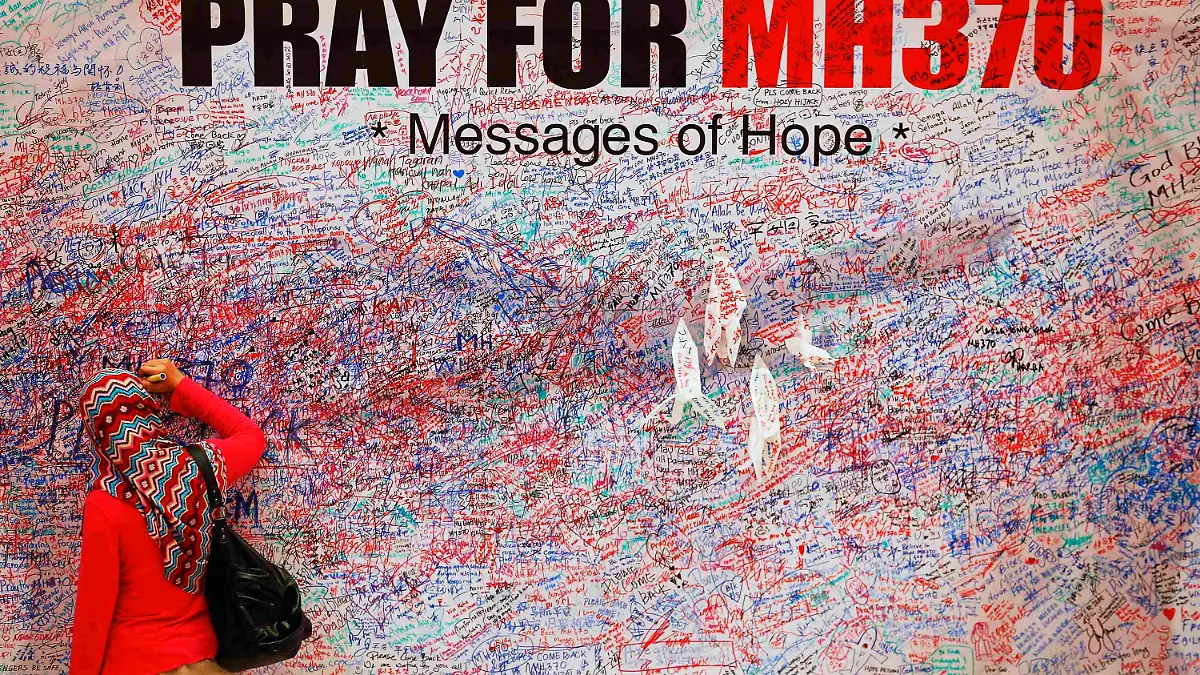 A woman leaves a messages of support and hope for the passengers of the missing Malaysia Airlines MH370 in central Kuala Lumpur March 16, 2014.  Police are combing through the personal, political and religious backgrounds of pilots and crew of the missing Malaysian jetliner, a senior officer said on Sunday, trying to work out why someone aboard flew the plane hundreds of miles off course. REUTERS/Damir Sagolj  (MALAYSIA - Tags: TRANSPORT DISASTER TPX IMAGES OF THE DAY)