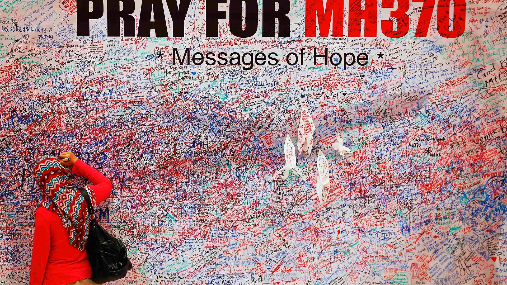 A woman leaves a messages of support and hope for the passengers of the missing Malaysia Airlines MH370 in central Kuala Lumpur March 16, 2014.  Police are combing through the personal, political and religious backgrounds of pilots and crew of the missing Malaysian jetliner, a senior officer said on Sunday, trying to work out why someone aboard flew the plane hundreds of miles off course. REUTERS/Damir Sagolj  (MALAYSIA - Tags: TRANSPORT DISASTER TPX IMAGES OF THE DAY)