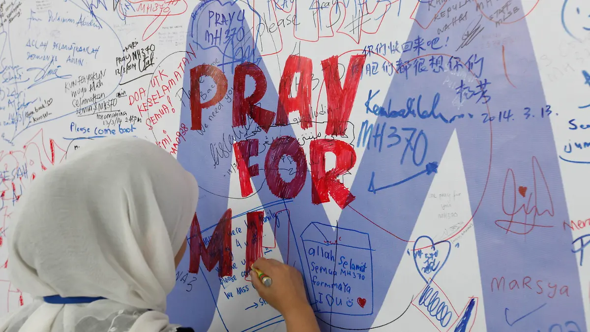 epa04124618 A well wisher writes a message for the passengers of a missing Malaysian Airline plane on a banner at Kuala Lumpur International Airport, Malaysia, 14 March 2014. Malaysia Airlines flight MH370 with 239 people on board went missing early 08 March 2014 while on its way to Beijing, China. Malaysia Airlines said in a statement that flight MH370 was carrying a total of 227 passengers, including two infants, and 12 crew members. The search for a missing Malaysia Airlines passenger jet on 14 March expanded westwards towards the Indian Ocean, amid new information gathered by US investigators that the aircraft may have flown for hours after it dropped off the radar. Search and rescue operations for the missing plane for the past six days have been focused in the South China Sea and the Malacca Strait. EPA/MAK REMISSA +++(c) dpa - Bildfunk+++