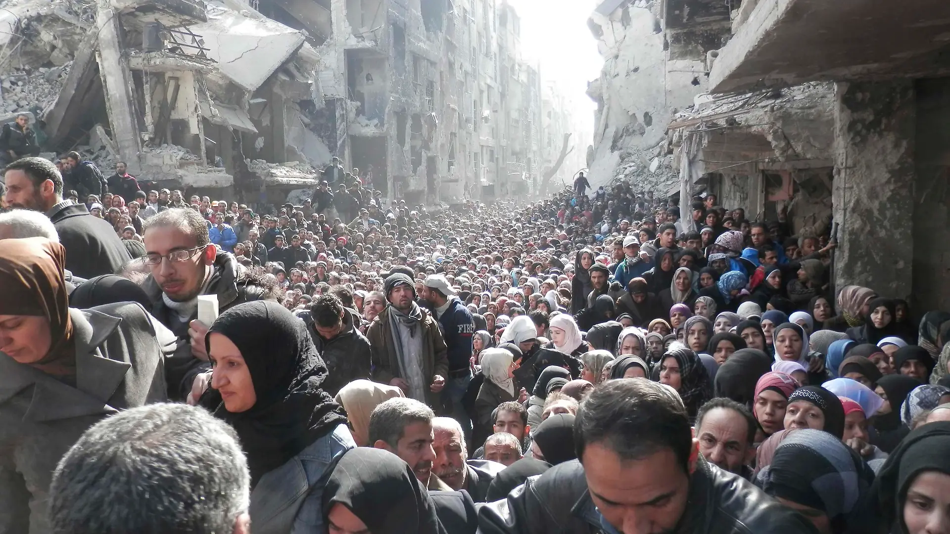 Residents wait to receive food aid distributed by the U.N. Relief and Works Agency (UNRWA) at the besieged al-Yarmouk camp, south of Damascus on January 31, 2014, in this handout picture made available to Reuters February 26, 2014. World powers have passed a landmark Security Council resolution demanding an end to restrictions on humanitarian operations in Syria, but aid workers doubt it has the punch to make Damascus grant access and let stuck convoys deliver vital supplies. The resolution called for the immediate lifting of sieges in specific towns and cities around the country, including Yarmouk, a Palestinian neighbourhood in Damascus that took in refugees after the creation of Israel, where people have been trapped for eight months by an army siege. Picture taken January 31, 2014.
REUTERS/UNRWA/Handout via Reuters (SYRIA - Tags: POLITICS CIVIL UNREST CONFLICT SOCIETY TPX IMAGES OF THE DAY) ATTENTION EDITORS - THIS IMAGE WAS PROVIDED BY A THIRD PARTY. FOR EDITORIAL USE ONLY. NOT FOR SALE FOR MARKETING OR ADVERTISING CAMPAIGNS. THIS PICTURE IS DISTRIBUTED EXACTLY AS RECEIVED BY REUTERS, AS A SERVICE TO CLIENTS