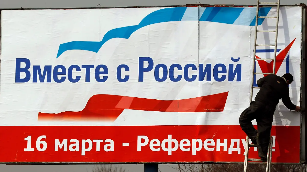 A worker puts up a poster that reads, "Together with Russia. March 16 - referendum", in the centre of Simferopol, March 12, 2014. Crimea will soon take ownership of Ukrainian state companies on its territory, its first deputy prime minister said on Wednesday, pushing forward with steps to cement the region's independence before a referendum on joining Russia. REUTERS/Vasily Fedosenko (UKRAINE - Tags: POLITICS ELECTIONS)