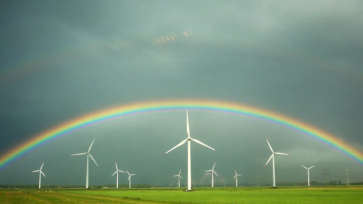 ARCHIV - Ein Regenbogen spannt sich am 18.08.2013 über grünen Feldern und Windkraftanlagen vor grauen Regenwolken bei Wilster (Schleswig-Holstein). Die Aufnahme entstand durch das Fenster eines Zuges. Die Energiepolitik und die Energiewende in Deutschland und Mecklenburg-Vorpommern sind die Hauptthemen des 3. Energieforums am 20.02.2014 in Schwerin. Foto: Christian Charisius/dpa (zu dpa "Energieforum zu Kommunal-Beteiligungen an Windparks" vom 20.02.2014) +++(c) dpa - Bildfunk+++