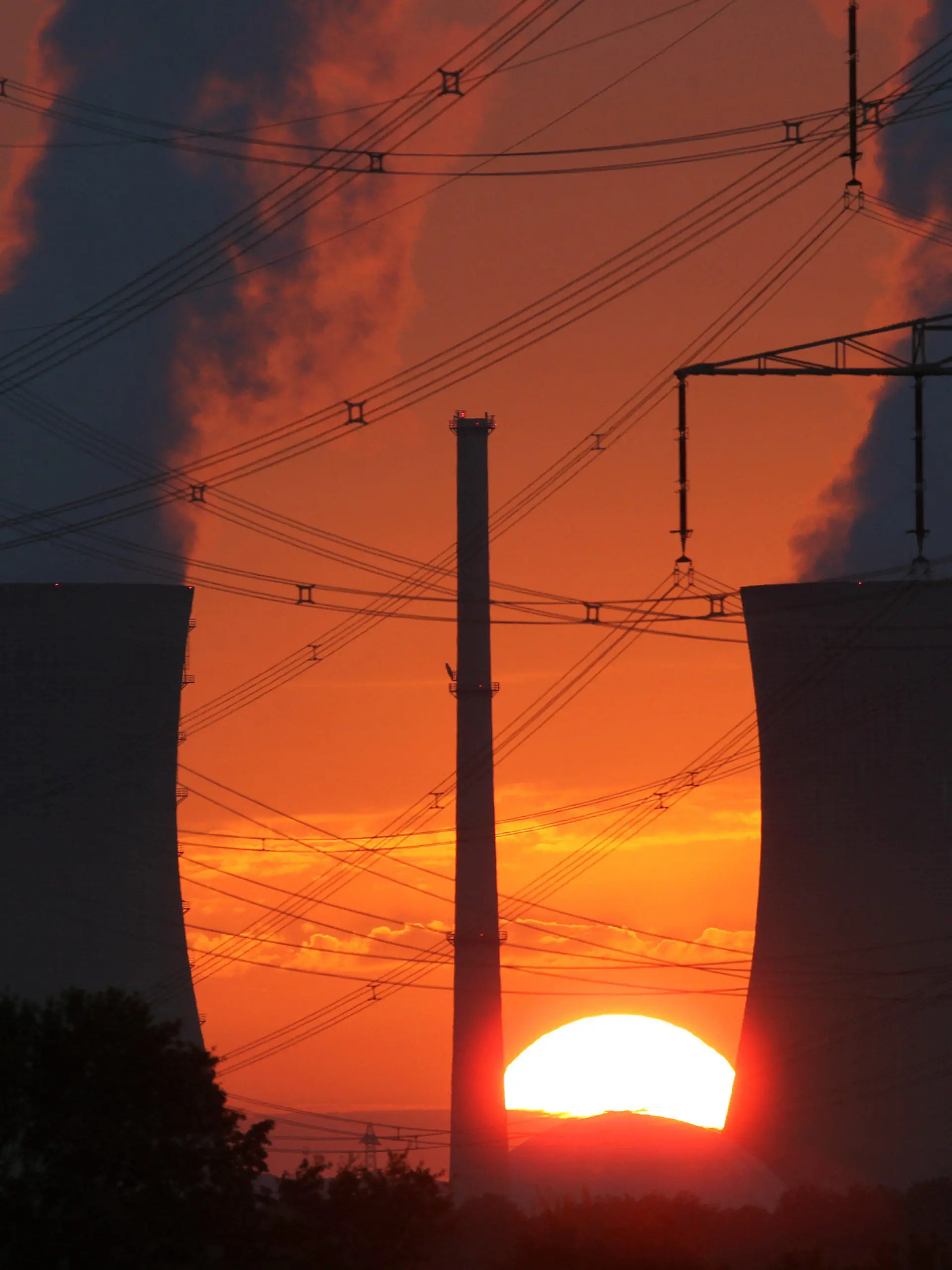 ARCHIV - Glühend rot ist der Himmel beim Sonneuntergang am Sonntagabend (21.08.2011) hinter den Kühltürmen des Atomkraftwerks Grafenrheinfeld (Unterfranken). Der Ausstoß von Treibhausgasen steigt dramatisch an, die Erderwärmung könnte unbeherrschbar werden. Dennoch scheint ein Durchbruch für mehr globalen Klimaschutz in einer Woche beim UN-Gipfel in Durban kaum möglich. Überlegt wird schon, einfach die Sonne abzuschirmen. Foto: Daniel Karmann dpa/lby (zu (THEMENPAKET Klimagipfel - zum 28. November, Letzte Ausfahrt Sonnenabschirmung?) +++(c) dpa - Bildfunk+++