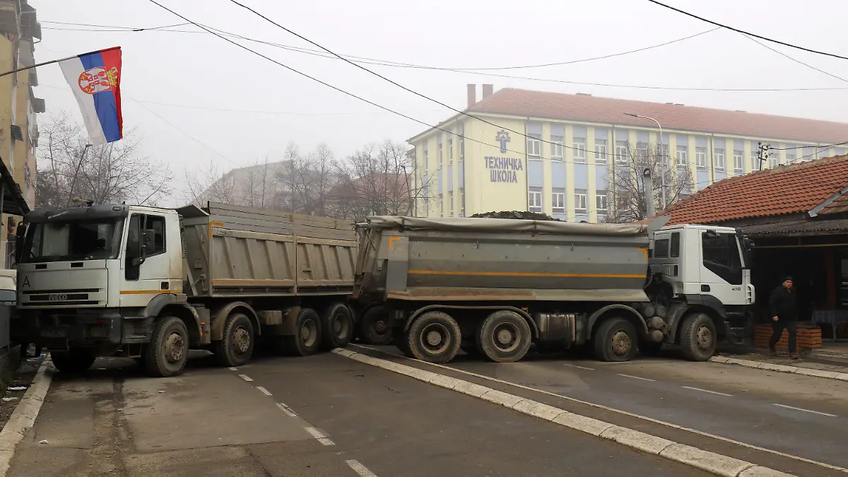 dpatopbilder - 27.12.2022, Kosovo, Mitrovica: Ein Mann geht an einer Barrikade aus mit Steinen beladenen Lastwagen vorbei, die in der Nacht auf einer Straße im nördlichen, serbisch dominierten Teil der ethnisch geteilten Stadt Mitrovica errichtet wurde. Militante Serben haben erstmals im Zuge der gegenwärtigen Spannungen im Kosovo eine Barrikade im Norden der geteilten Stadt Mitrovica errichtet. Foto: Bojan Slavkovic/AP/dpa +++ dpa-Bildfunk +++