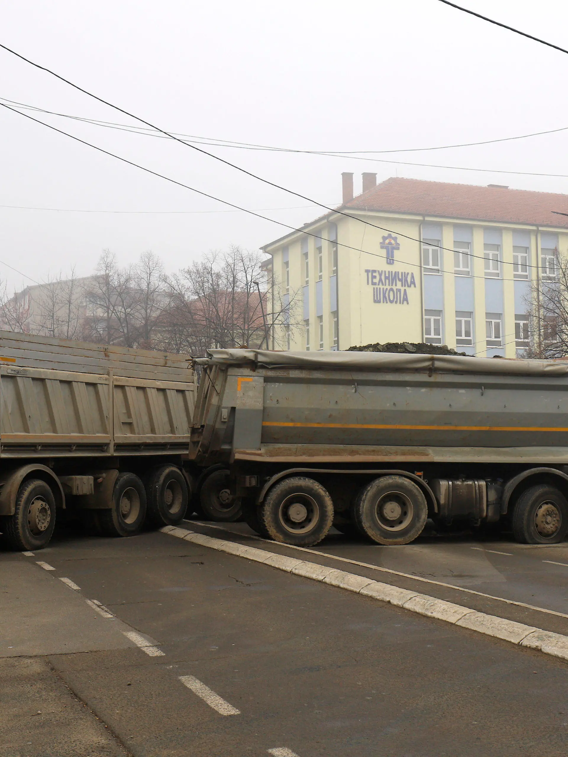dpatopbilder - 27.12.2022, Kosovo, Mitrovica: Ein Mann geht an einer Barrikade aus mit Steinen beladenen Lastwagen vorbei, die in der Nacht auf einer Straße im nördlichen, serbisch dominierten Teil der ethnisch geteilten Stadt Mitrovica errichtet wurde. Militante Serben haben erstmals im Zuge der gegenwärtigen Spannungen im Kosovo eine Barrikade im Norden der geteilten Stadt Mitrovica errichtet. Foto: Bojan Slavkovic/AP/dpa +++ dpa-Bildfunk +++