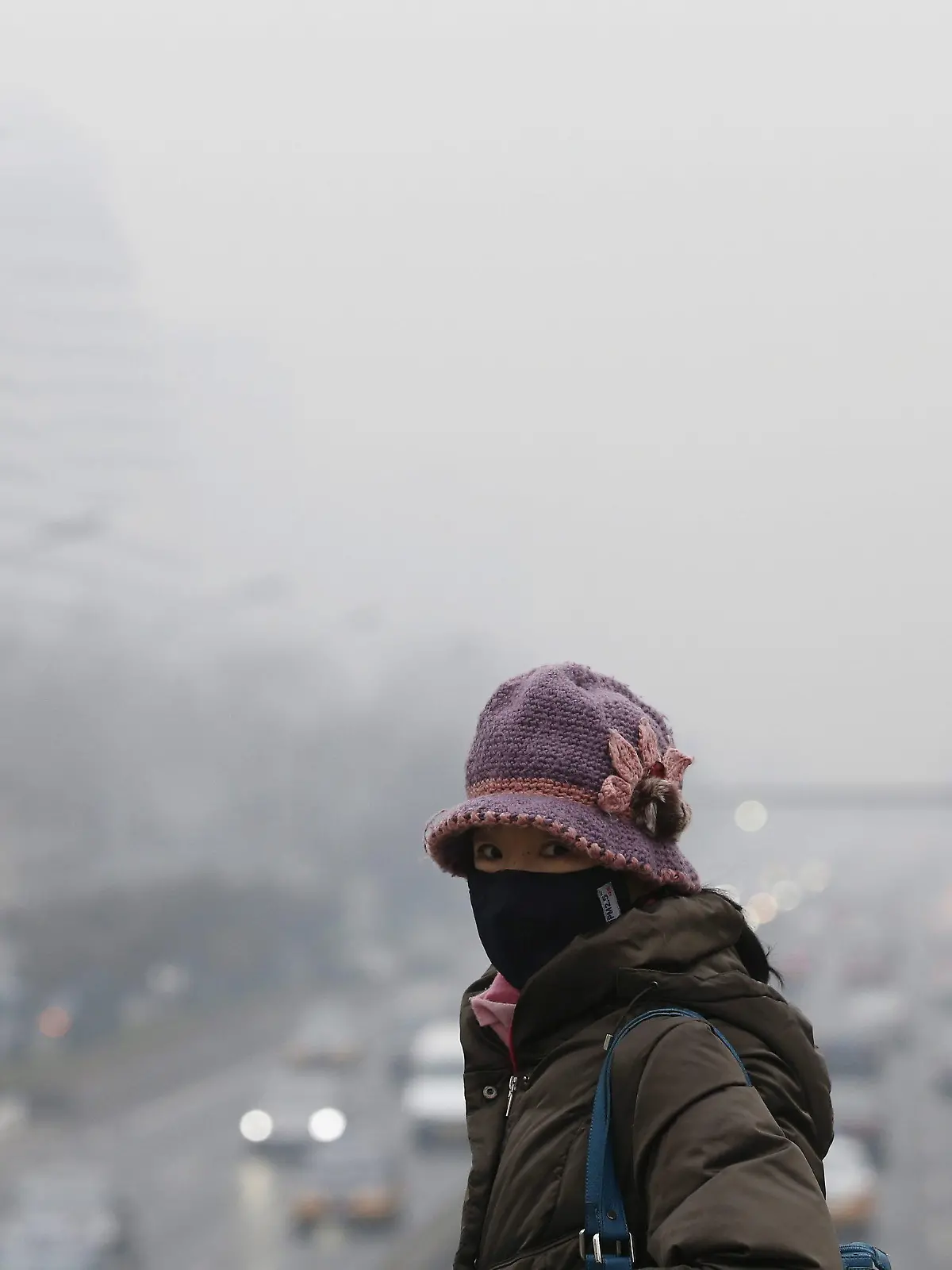 epa04098578 A woman wearing a protective mask walks along a commuter bridge overlooking a main road amidst smog in Beijing, China, 24 February 2014. Due to smog alerts, a city in northern China has banned a fifth of residents' vehicles from roads, reports stated since 23 February. In Beijing, an orange alert had been issued on 21 February due to smog which is the second-highest of four levels of urgency. The Environmental Protection Ministry has sent 12 inspection teams to Beijing, Tianjin, Hebei and surrounding areas to check on compliance to measures to reduce air pollution. EPA/ROLEX DELA PENA +++(c) dpa - Bildfunk+++