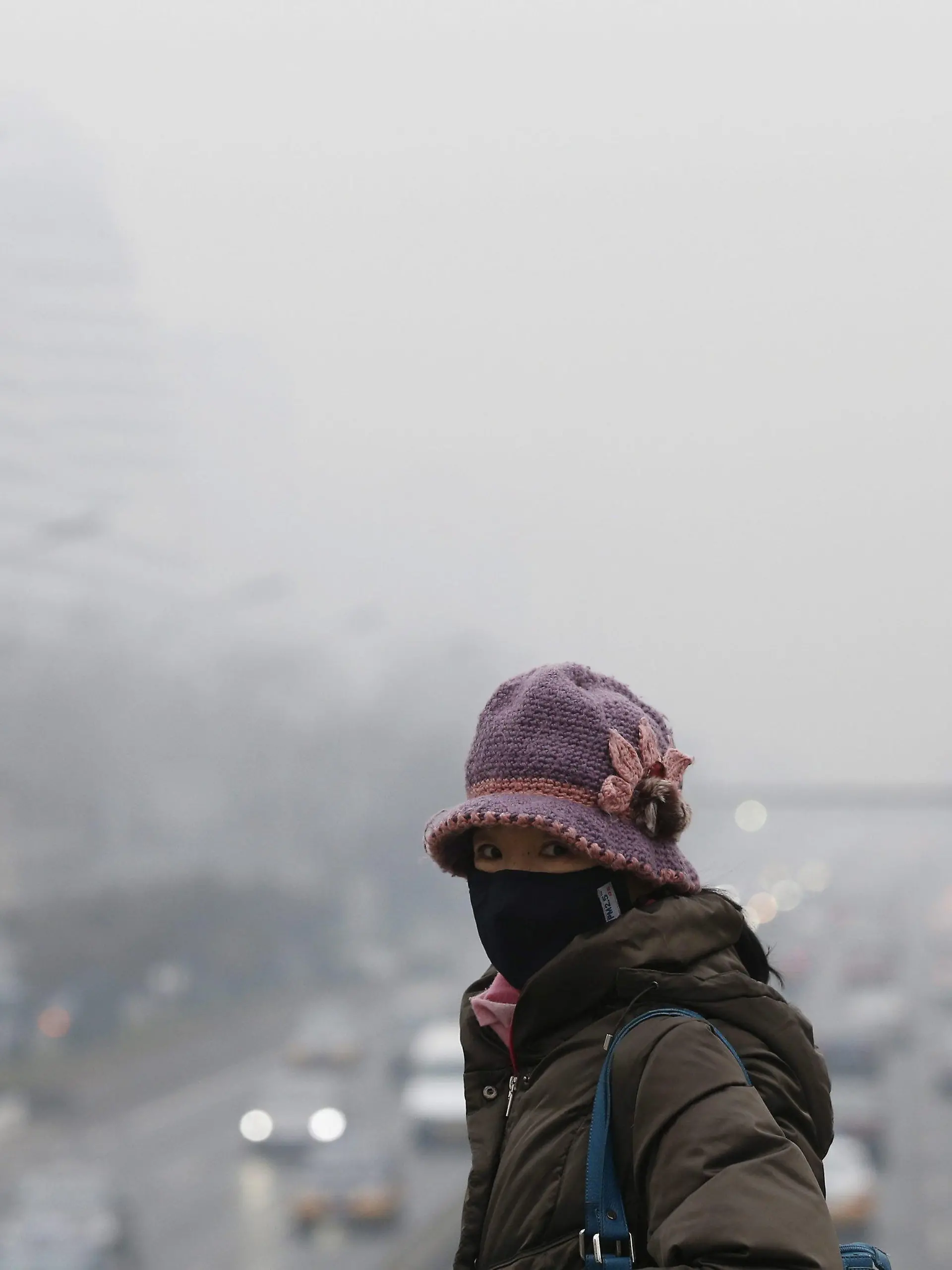epa04098578 A woman wearing a protective mask walks along a commuter bridge overlooking a main road amidst smog in Beijing, China, 24 February 2014. Due to smog alerts, a city in northern China has banned a fifth of residents' vehicles from roads, reports stated since 23 February. In Beijing, an orange alert had been issued on 21 February due to smog which is the second-highest of four levels of urgency. The Environmental Protection Ministry has sent 12 inspection teams to Beijing, Tianjin, Hebei and surrounding areas to check on compliance to measures to reduce air pollution. EPA/ROLEX DELA PENA +++(c) dpa - Bildfunk+++