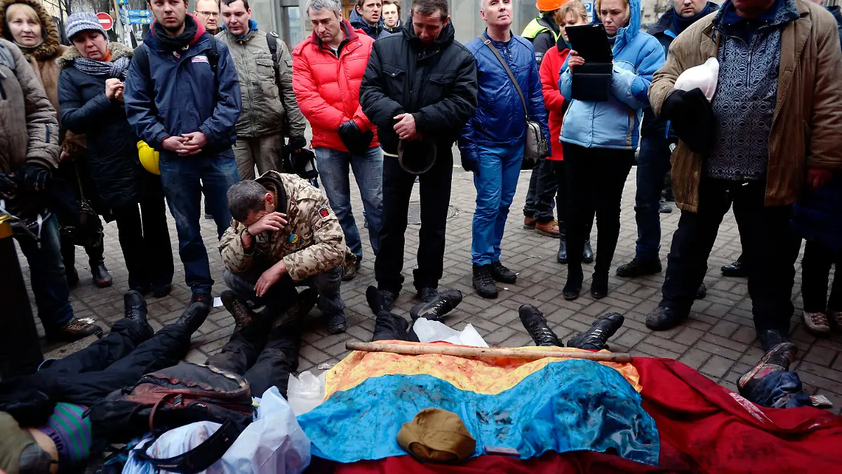 epa04090926 Activists pay respects to protesters killed in clashes with police in Kiev, Ukraine, 20 February 2014. More than 60 people have been killed in street fighting in Kiev on Thursday, the nationalist Svoboda opposition party says. The Ukrainian police force has been given combat weapons for use in the civil unrest in Kiev, Interior Minister Vitaliy Zakharchenko says. Fresh fighting broke out between thousands of protesters and riot police on Kiev's Independence Square only hours after opposition leaders and President Viktor Yanukovych declared a truce. Protesters were seen throwing firebombs and molotov cocktails at police, who responded with teargas. The square was filled with black smoke from burning tyres. EPA/LASZLO BELICZAY ATTENTION EDITORS: GRAPHIC CONTENT +++(c) dpa - Bildfunk+++