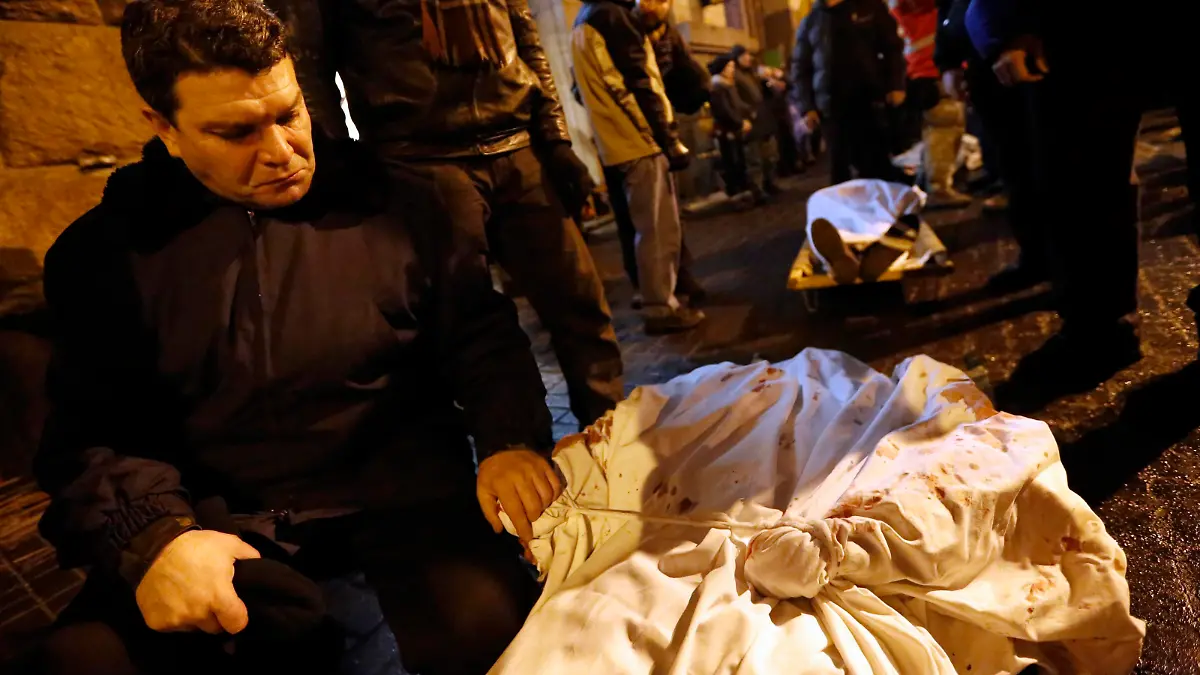 A man holds the hand of his dead son during the transfer of over a dozen of corpses from a hotel lobby to a local hospital following clashes with riot police at Independence Square in Kiev February 20, 2014. Ukraine suffered its bloodiest day since Soviet times on Thursday with a gun battle in central Kiev as President Viktor Yanukovich faced conflicting pressures from visiting European Union ministers and his Russian paymasters.   REUTERS/Yannis Behrakis (UKRAINE - Tags: CIVIL UNREST POLITICS TPX IMAGES OF THE DAY)