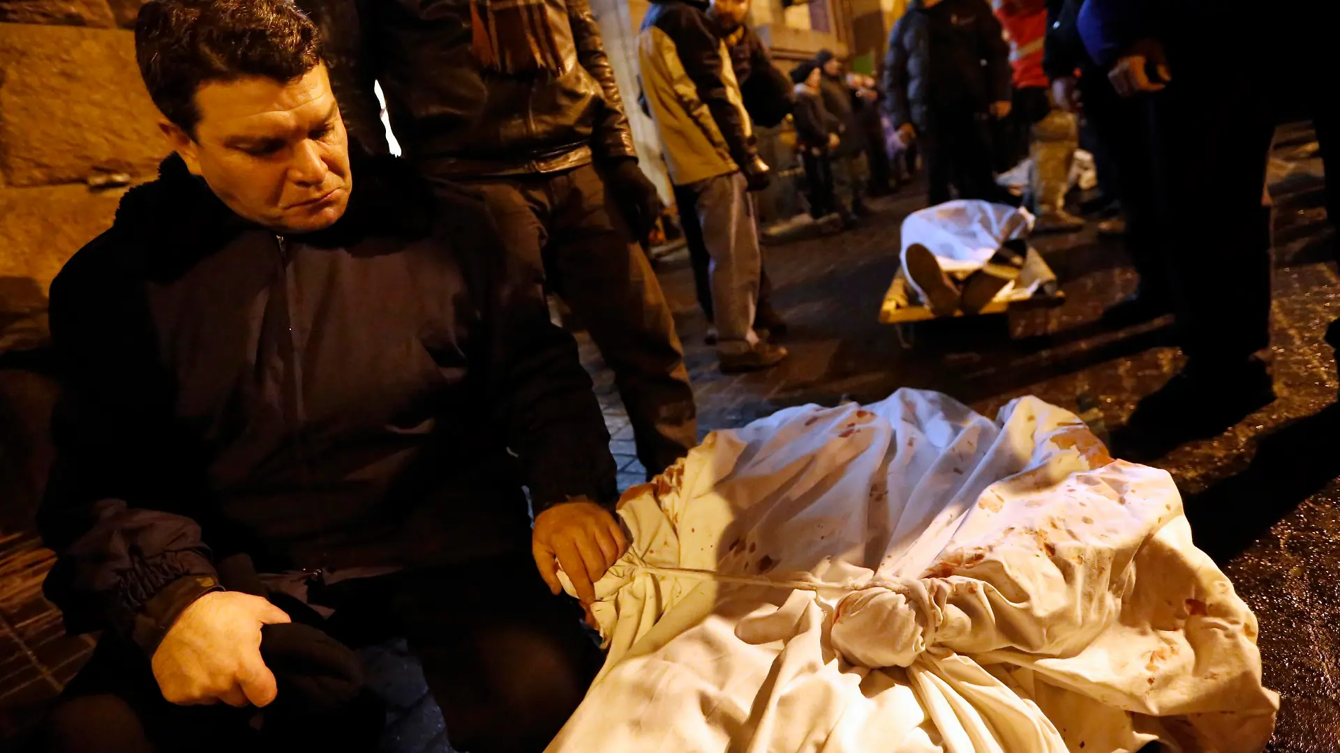 A man holds the hand of his dead son during the transfer of over a dozen of corpses from a hotel lobby to a local hospital following clashes with riot police at Independence Square in Kiev February 20, 2014. Ukraine suffered its bloodiest day since Soviet times on Thursday with a gun battle in central Kiev as President Viktor Yanukovich faced conflicting pressures from visiting European Union ministers and his Russian paymasters.   REUTERS/Yannis Behrakis (UKRAINE - Tags: CIVIL UNREST POLITICS TPX IMAGES OF THE DAY)