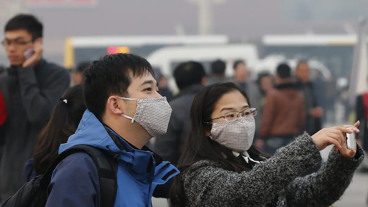 (FILE) epa03980637 A Chinese couple wear protective masks while going around the Tiananmen Square, which is seen with a hazy atmosphere around the Forbidden City in Beijing, China, 07 December 2013. EPA/ROLEX DELA PENA (zu dpa "Smog hält Peking im Würgegriff ..." vom 16.02.2014) +++(c) dpa - Bildfunk+++