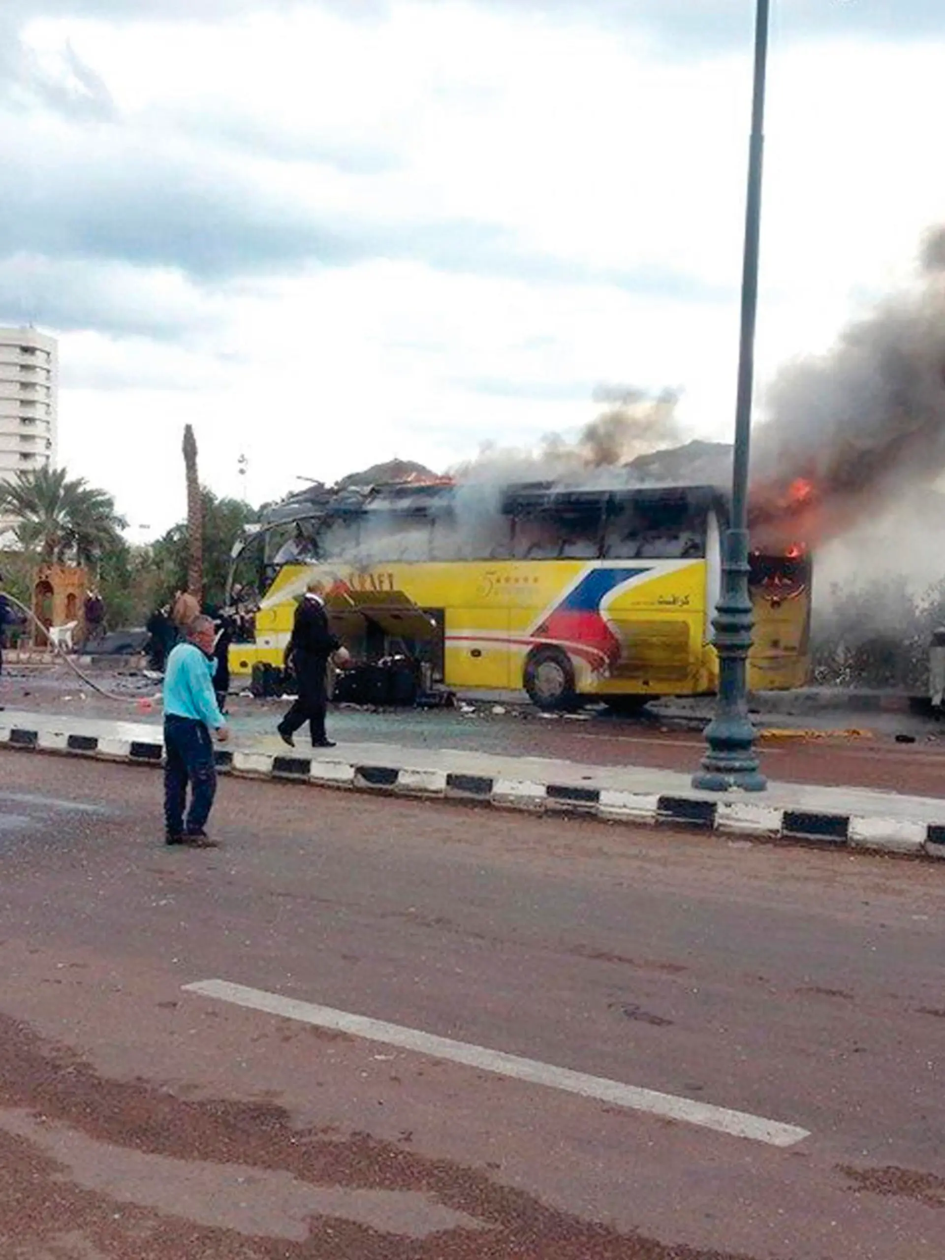 People and security officials walk and look as smoke rises from a tourist bus in the Red Sea resort town of Taba in the south Sinai, February 16, 2014. An explosion on a  tourist bus in Egypt's Sinai peninsula killed three Koreans and the Egyptian  driver on Sunday, the Interior Ministry said, an apparent turning point in an  Islamist insurgency that has gained pace since an army takeover in July. REUTERS/Stringer (EGYPT - Tags: POLITICS CIVIL UNREST TPX IMAGES OF THE DAY)