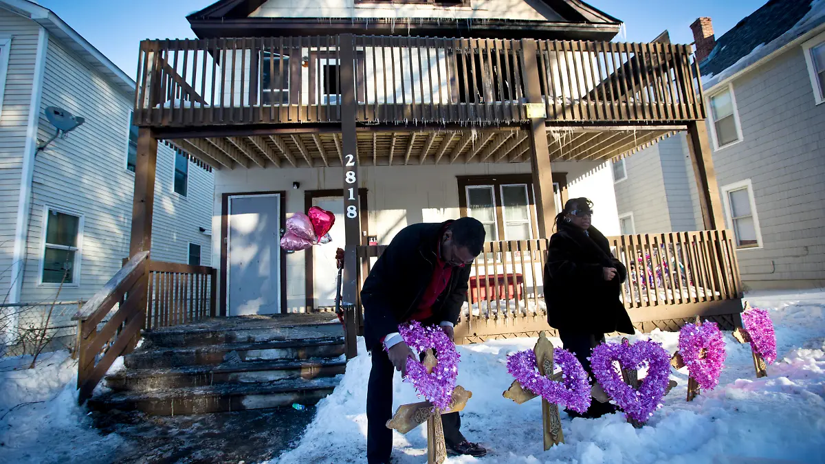 John Martin and Helen Williams put five crosses and wreaths in front of the home where people were killed in a house fire on Friday, Feb. 14, 2014, in Minneapolis. The fire killed five people, including at least three children, and injured several others, officials said. (AP Photo/The Star Tribune, Renee Jones Schneider)