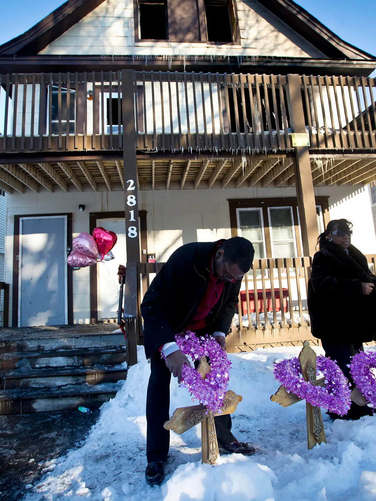 John Martin and Helen Williams put five crosses and wreaths in front of the home where people were killed in a house fire on Friday, Feb. 14, 2014, in Minneapolis. The fire killed five people, including at least three children, and injured several others, officials said. (AP Photo/The Star Tribune, Renee Jones Schneider)