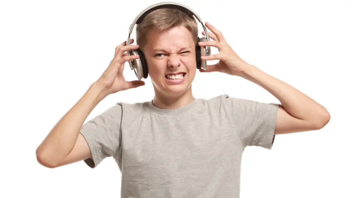 Angry teenage boy takes off headphones. Isolated on white background