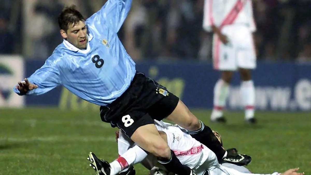 Uruguays Spieler Fabian O'Neill (oben) wird von einem nicht identifizierten peruanischen Gegenspieler gestoppt. Die Fußballnationalmannschaften von Uruguay und Peru trennen sich am 26.07.2000 im WM-Qualifikationsspiel im Centenario-Stadion in Montevideo torlos.