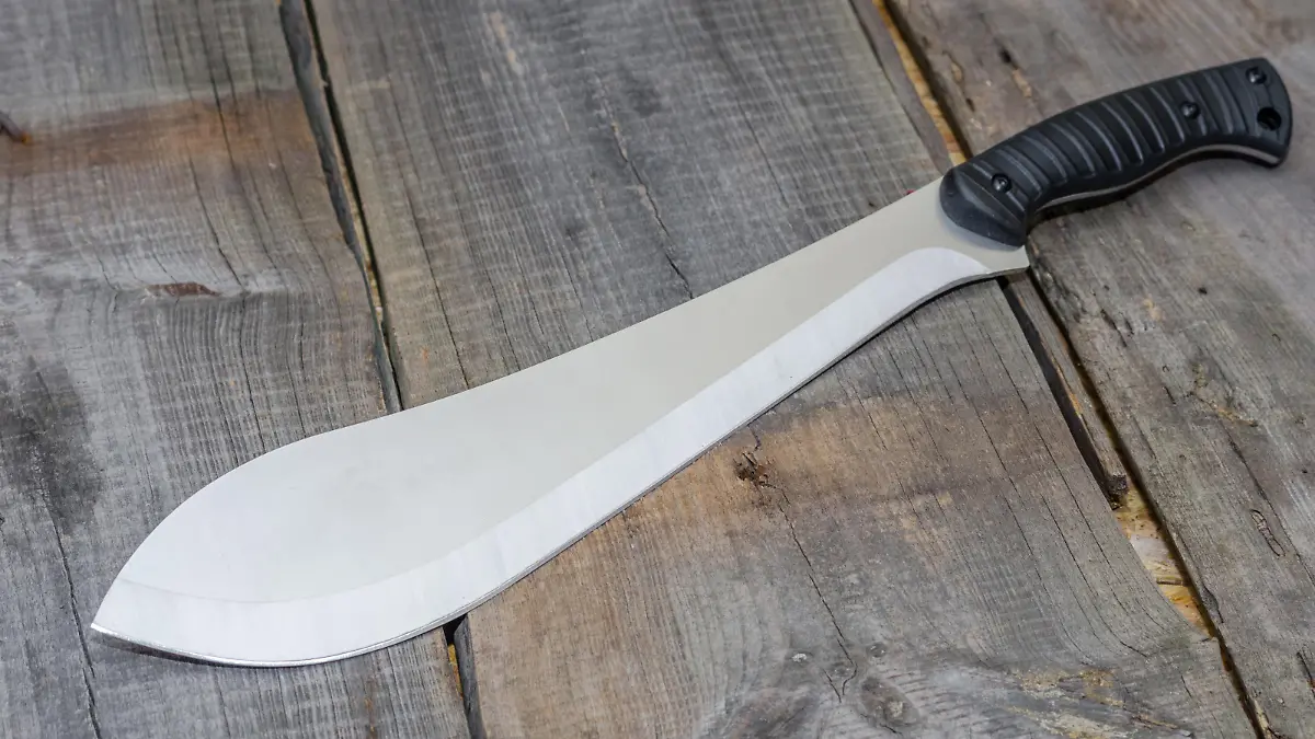 A Latin American knife for clearing roads. Photo at an angle. Wooden background.