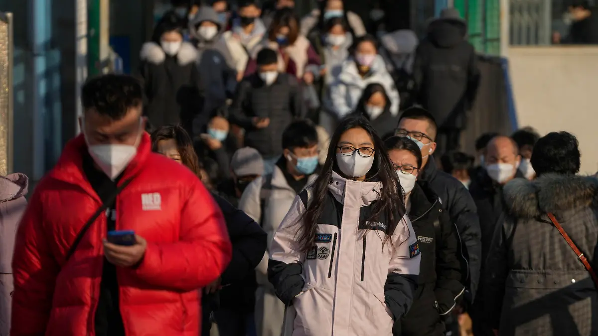 ARCHIV - 08.12.2022, China, Peking: Maskierte Pendler verlassen, während des morgendlichen Berufsverkehrs, eine U-Bahn-Station. Zwei Wochen nach dem abrupten Ende der strikten Null-Covid-Strategie in China erlauben zahlreiche Städte den Infizierten ohne oder mit nur milden Symptomen sogar die Rückkehr an den Arbeitsplatz.  (zu dpa «Nach Ende von Null-Covid: Infizierte dürfen in China sogar arbeiten») Foto: Andy Wong/AP/dpa +++ dpa-Bildfunk +++