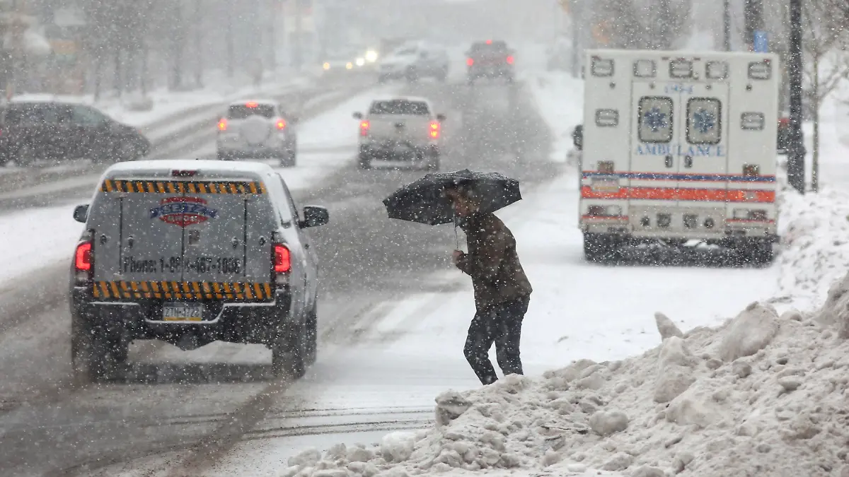 dpatopbilder - 22.12.2022, USA, Hazleton: Eine Person überquert eine Straße, während sie sich mit einem Regenschirm vor dem beginnenden Schneefall schützt. Ein arktisches Sturmtief bringt über die Weihnachtstage drastische Temperaturstürze und extreme Kälte in die USA. Foto: John Haeger/Standard-Speaker/AP/dpa +++ dpa-Bildfunk +++