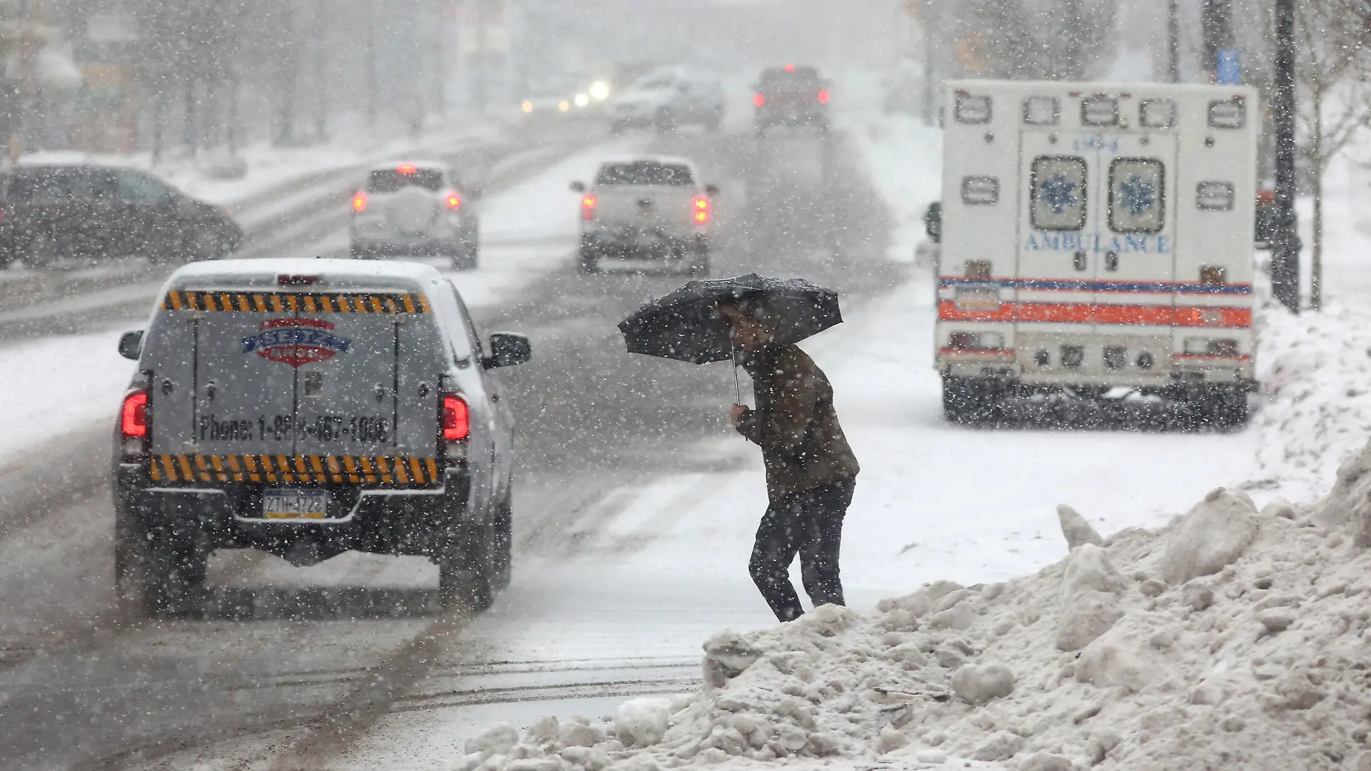 dpatopbilder - 22.12.2022, USA, Hazleton: Eine Person überquert eine Straße, während sie sich mit einem Regenschirm vor dem beginnenden Schneefall schützt. Ein arktisches Sturmtief bringt über die Weihnachtstage drastische Temperaturstürze und extreme Kälte in die USA. Foto: John Haeger/Standard-Speaker/AP/dpa +++ dpa-Bildfunk +++