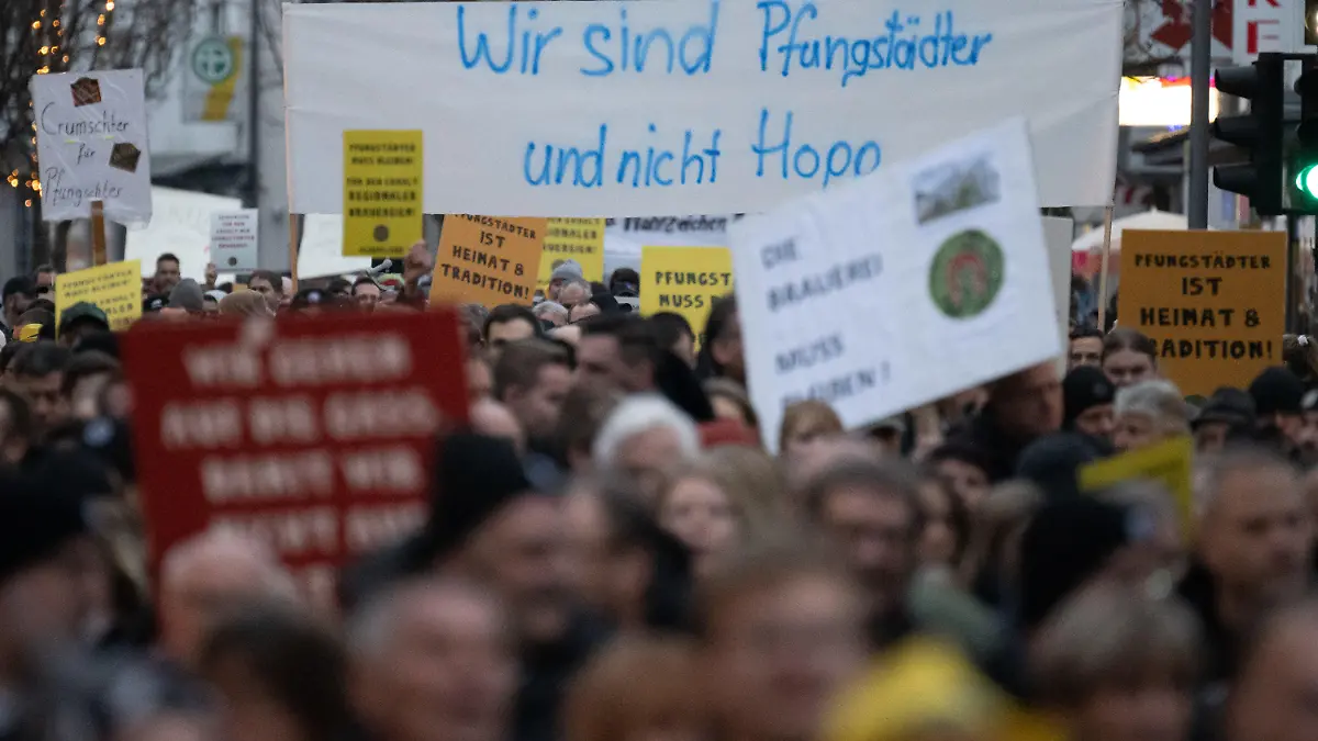22.12.2022, Hessen, Pfungstadt: Teilnehmer halte während einer Demonstration zum Erhalt der Brauerei Pfungstädter einen Banner hoch, auf dem steht «Wir sind Pfungstädter und nicht Hopp». Geplant ist, dass auf dem Gelände der Brauerei Wohnungen gebaut werden sollen. Foto: Sebastian Gollnow/dpa +++ dpa-Bildfunk +++
