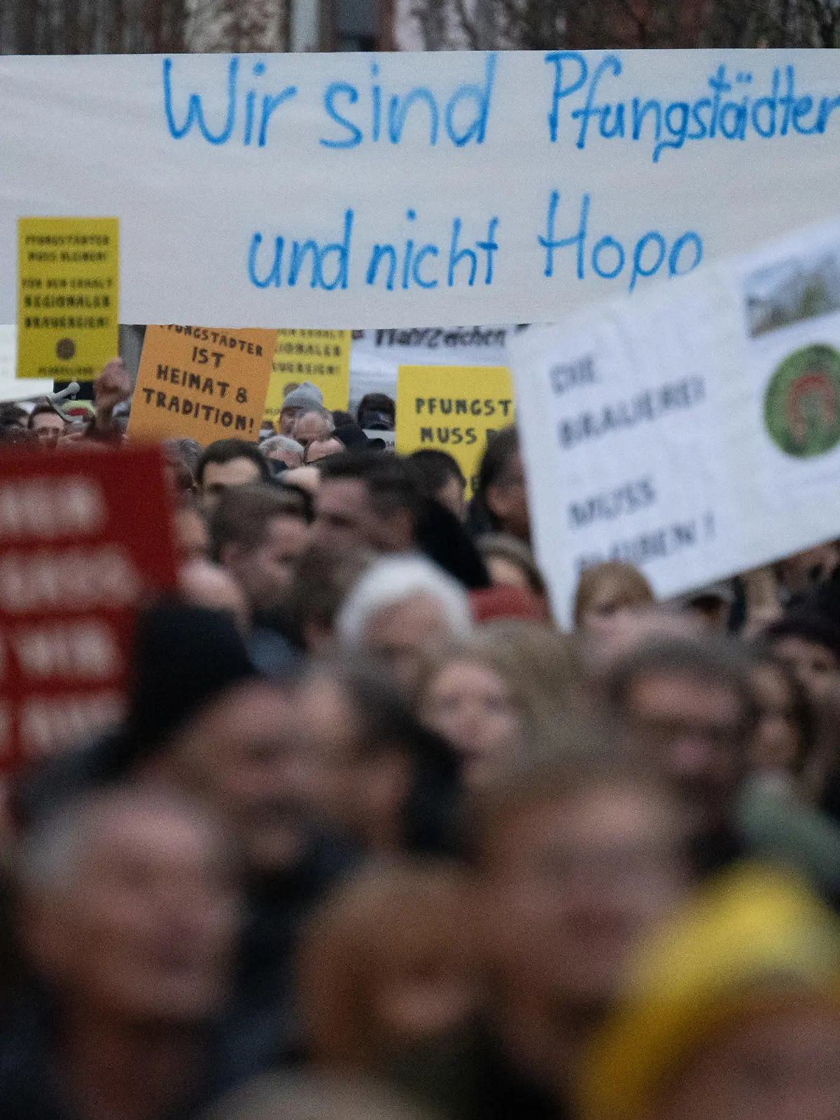 22.12.2022, Hessen, Pfungstadt: Teilnehmer halte während einer Demonstration zum Erhalt der Brauerei Pfungstädter einen Banner hoch, auf dem steht «Wir sind Pfungstädter und nicht Hopp». Geplant ist, dass auf dem Gelände der Brauerei Wohnungen gebaut werden sollen. Foto: Sebastian Gollnow/dpa +++ dpa-Bildfunk +++