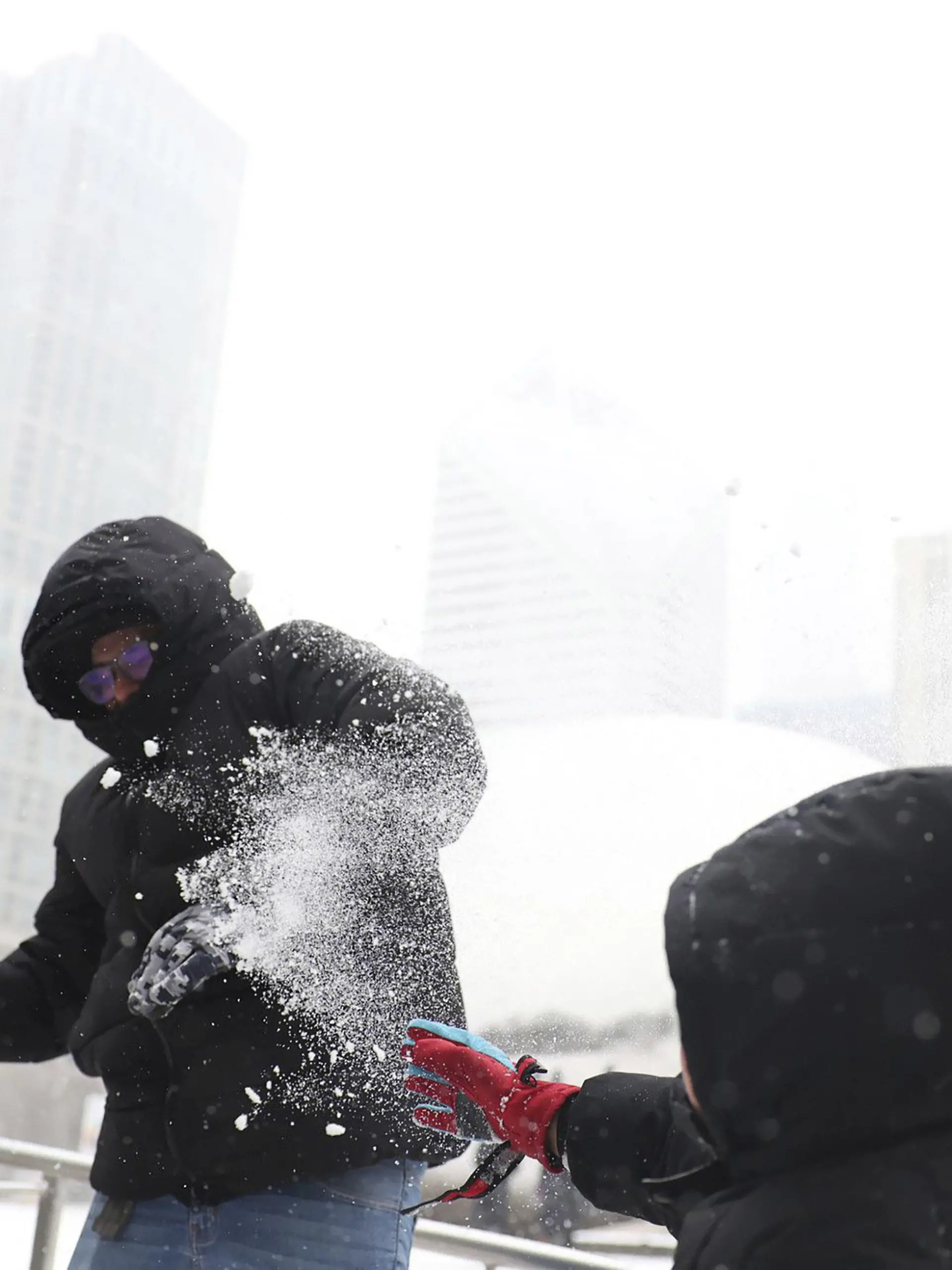 22.12.2022, USA, Chicago: Andres Garduno (l) liefert sich mit seinem Sohn Matteo Jimenez Garduno, beide aus Mexiko, während des Wintersturms am Donnerstag auf der Eisbahn im Millennium Park eine Schneeschlacht. In ganz Chicago fiel heute Schnee, und die Temperaturen sollen bis zum Abend drastisch sinken. Die USA bereiten sich auf einen «historischen» Wintersturm kurz vor den Weihnachtsfeiertagen vor. Eine arktische Kaltfront werde in der Nacht von Donnerstag auf Freitag (Ortszeit) über Teile im Osten Landes hinwegziehen, warnte der US-Wetterdienst. Das Sturmtief werde extreme Kälte, heftige Schneefälle und Eiswind bringen. Foto: Michael Blackshire/Chicago Tribune via ZUMA Press/dpa +++ dpa-Bildfunk +++